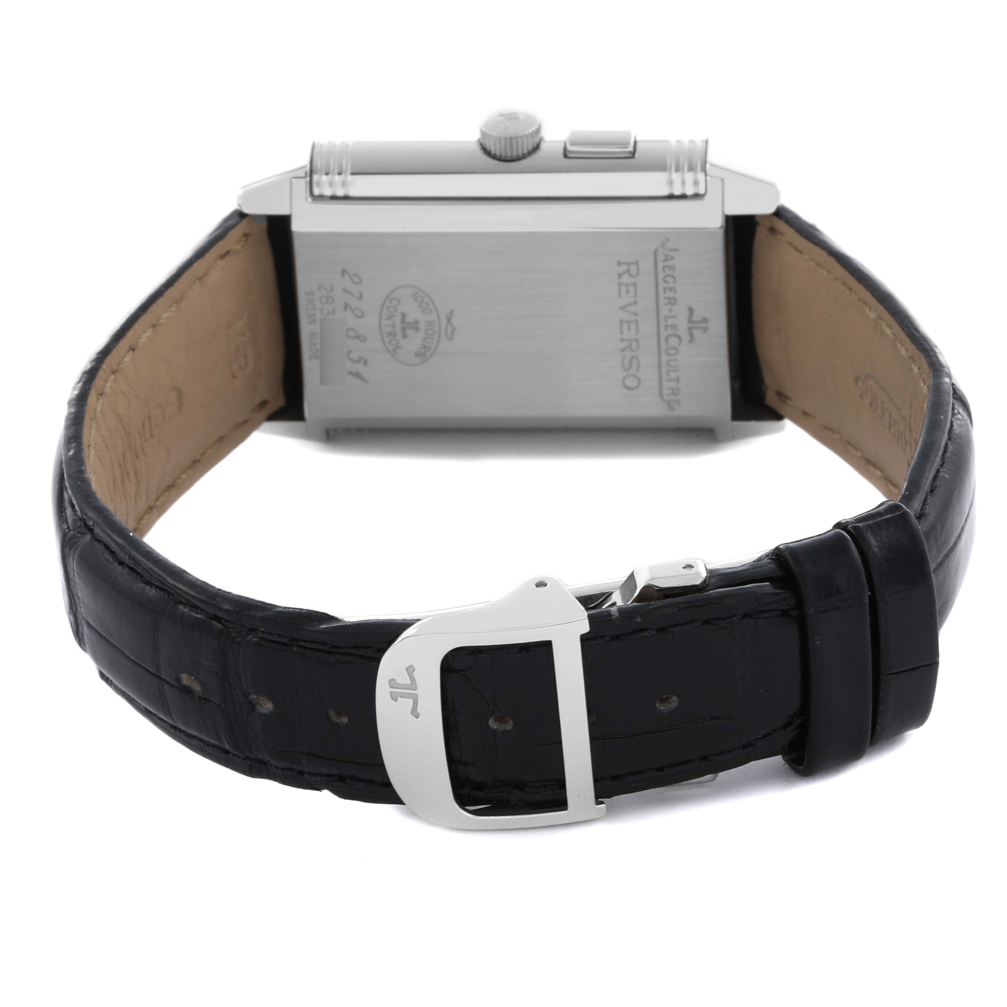 The image shows the back of a Jaeger-LeCoultre Reverso watch with an opened black leather strap and visible buckle.