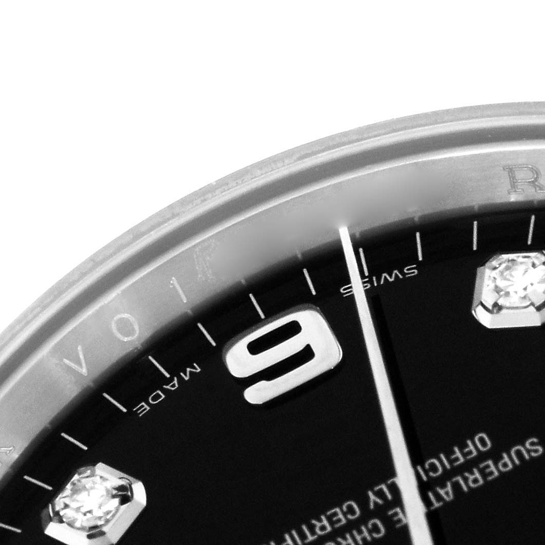 The image shows a close-up of a Rolex Date 115234 Men's Stainless Steel Black Dial 115234 Men's Stainless Steel Black Dial watch dial, highlighting the number 9, hour markers, and some text.