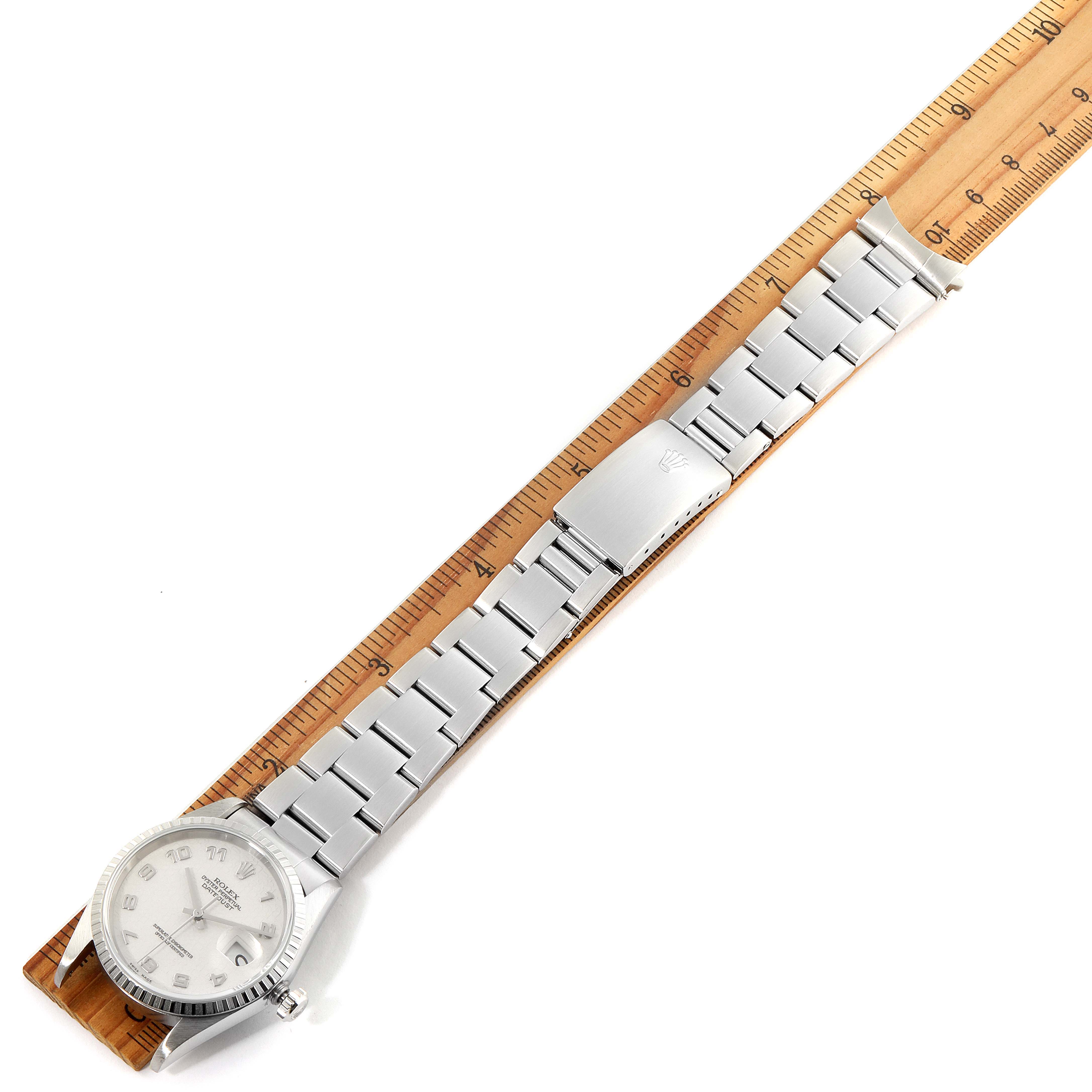 The image shows a Rolex Datejust 16220 Men
s Stainless Steel Silver Dial 16220 Men
s Stainless Steel Silver Dial watch laid flat next to a ruler, displaying the full bracelet and dial.