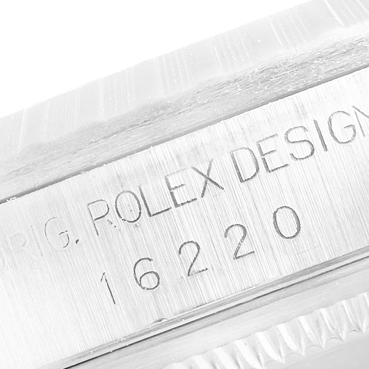 This close-up image shows the engraved reference number and "ROLEX DESIGN" on the side of a Rolex Datejust 16220 Men
s Stainless Steel Silver Dial 16220 Men
s Stainless Steel Silver Dial watch case.
