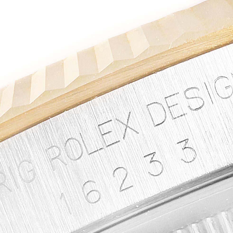 This close-up image of the Rolex Datejust 16233G Men's Steel and Gold (two tone) Silver Dial 16233G Men's Steel and Gold (two tone) Silver Dial model shows the engraved bezel and part of the fluted edge.