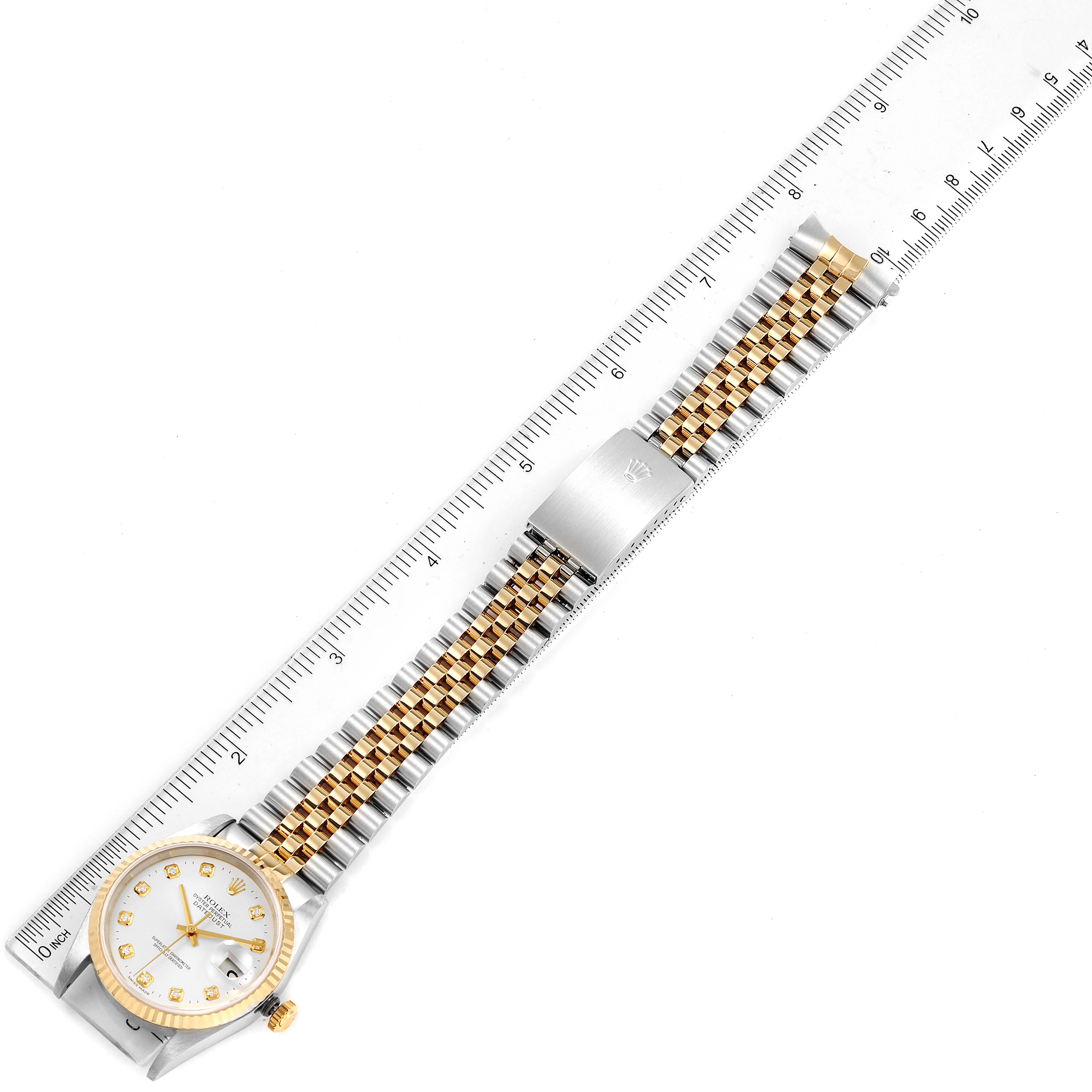 The image shows a top-down view of a Rolex Datejust 16233 Men's Steel and Gold (two tone) Silver Dial 16233 Men's Steel and Gold (two tone) Silver Dial watch with a two-tone bracelet and a ruler for scale.