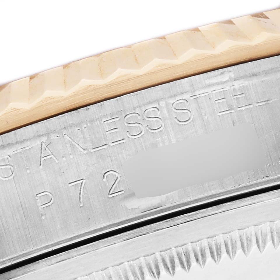 The image shows a close-up of the Rolex Datejust 16233 Men's Steel and Gold (two tone) White Dial 16233 Men's Steel and Gold (two tone) White Dial's stainless steel case and fluted bezel at an angle highlighting the engraving.