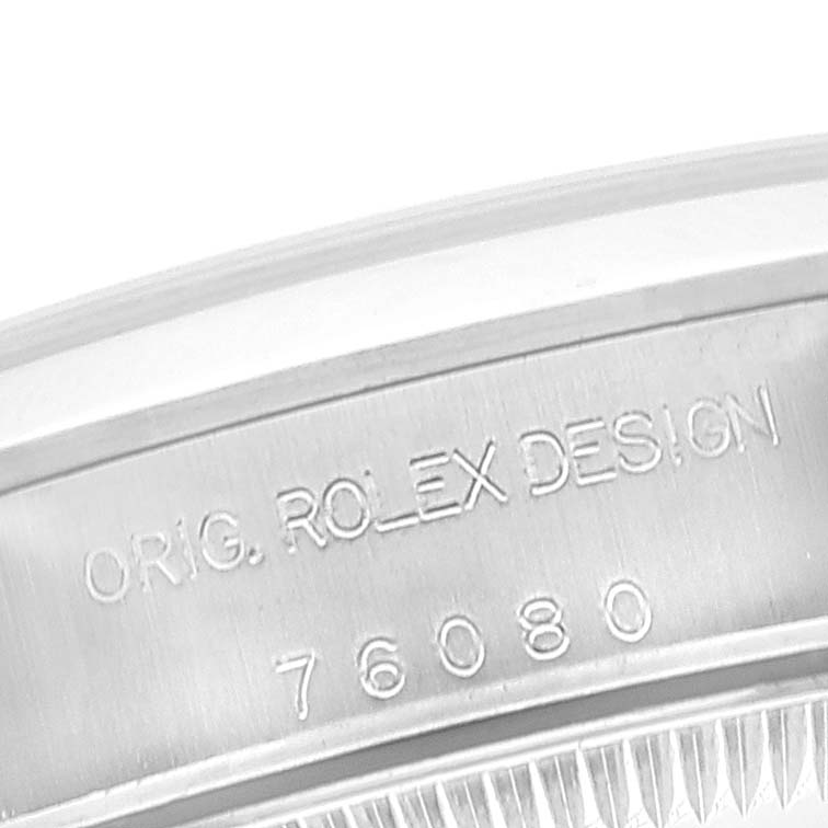This close-up image shows the engraved side of the Rolex Oyster Perpetual 76080 Women's Stainless Steel Black Dial 76080 Women's Stainless Steel Black Dial Model, displaying "ORIG. ROLEX DESIGN 76080."