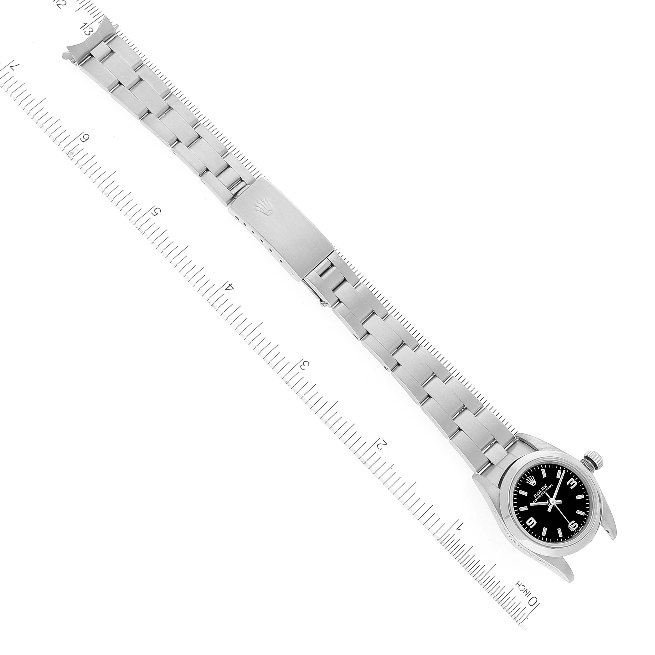 The image shows a top-down view of a Rolex Oyster Perpetual 76080 Women's Stainless Steel Black Dial 76080 Women's Stainless Steel Black Dial watch, highlighting the face, bezel, and bracelet with a ruler for scale.