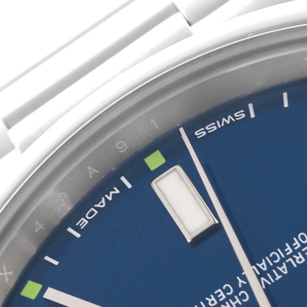 The image shows a close-up of the dial and part of the bracelet of a Rolex Oyster Perpetual 114300 Men's Stainless Steel Blue Dial 114300 Men's Stainless Steel Blue Dial watch.