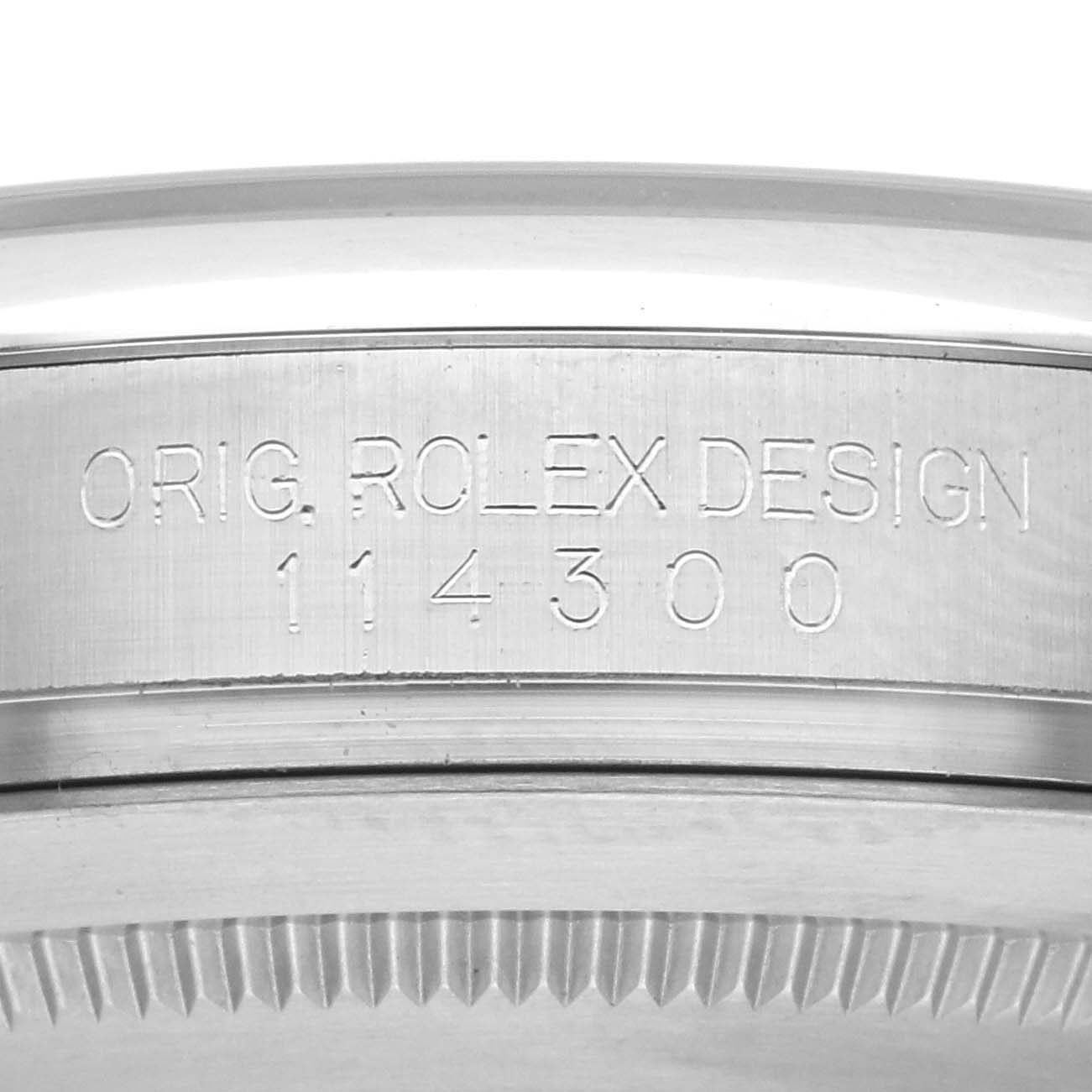 The image shows the side engraving of a Rolex Oyster Perpetual 114300 Men's Stainless Steel Blue Dial 114300 Men's Stainless Steel Blue Dial watch, highlighting its model number.