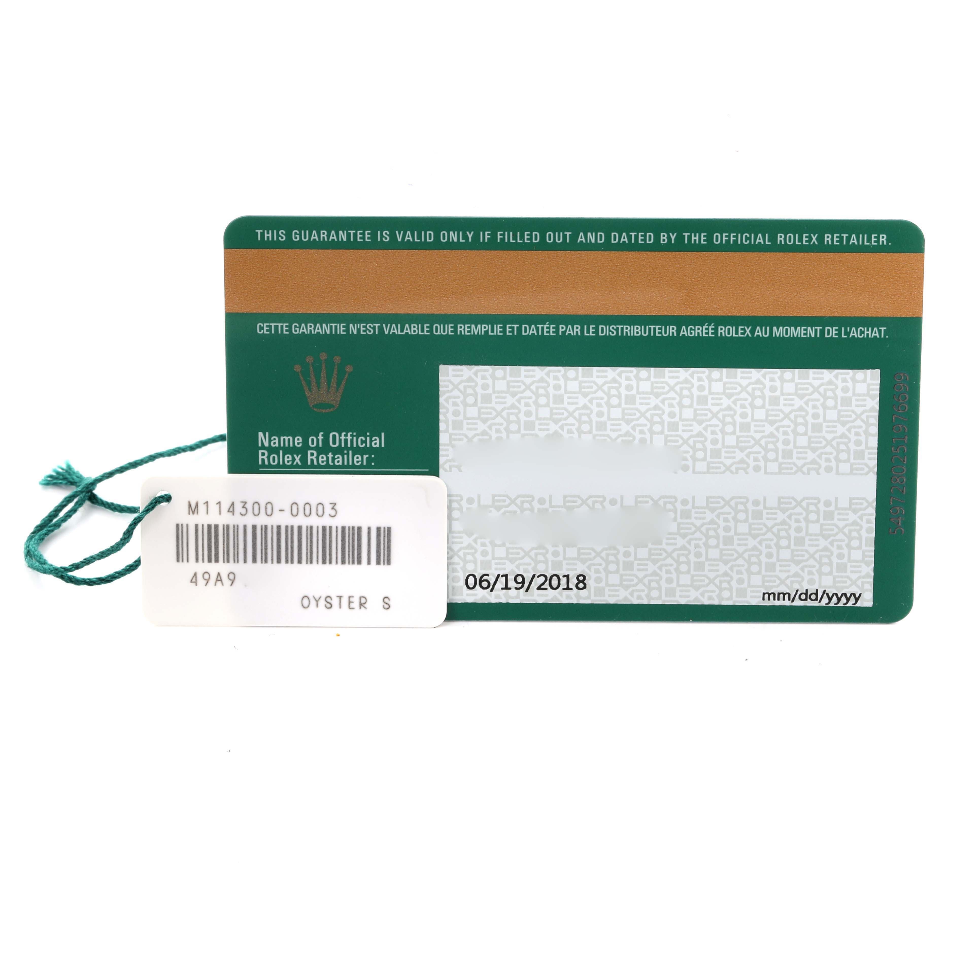 This image shows the authenticity card and tag for a Rolex Oyster Perpetual 114300 Men's Stainless Steel Blue Dial 114300 Men's Stainless Steel Blue Dial model, viewed from above.