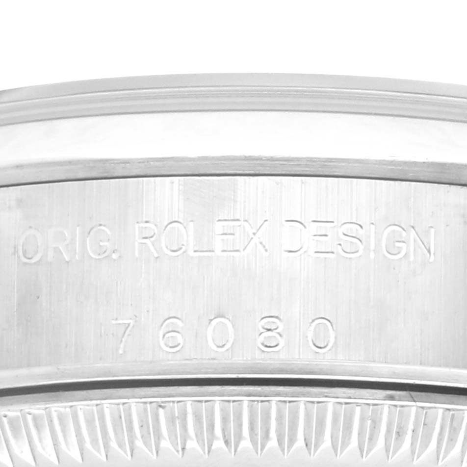 The image shows a close-up of the side of the Rolex Oyster Perpetual 76080 Women's Stainless Steel Brown Dial 76080 Women's Stainless Steel Brown Dial case, with design and model engraving visible.