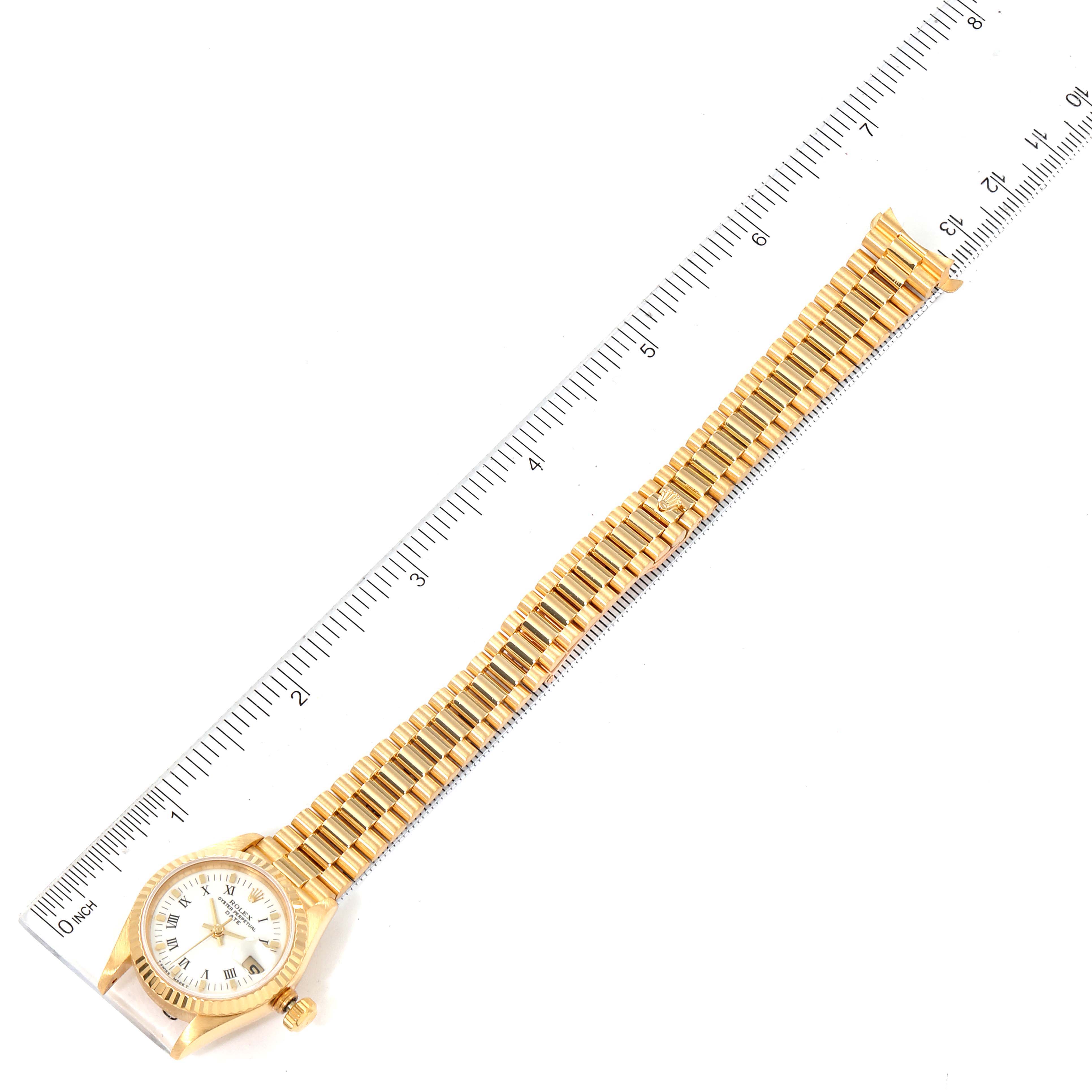 The image shows a top-down view of a Rolex President 69178 Women's Yellow Gold White Dial 69178 Women's Yellow Gold White Dial model watch, including the bracelet and the face next to a ruler for scale.