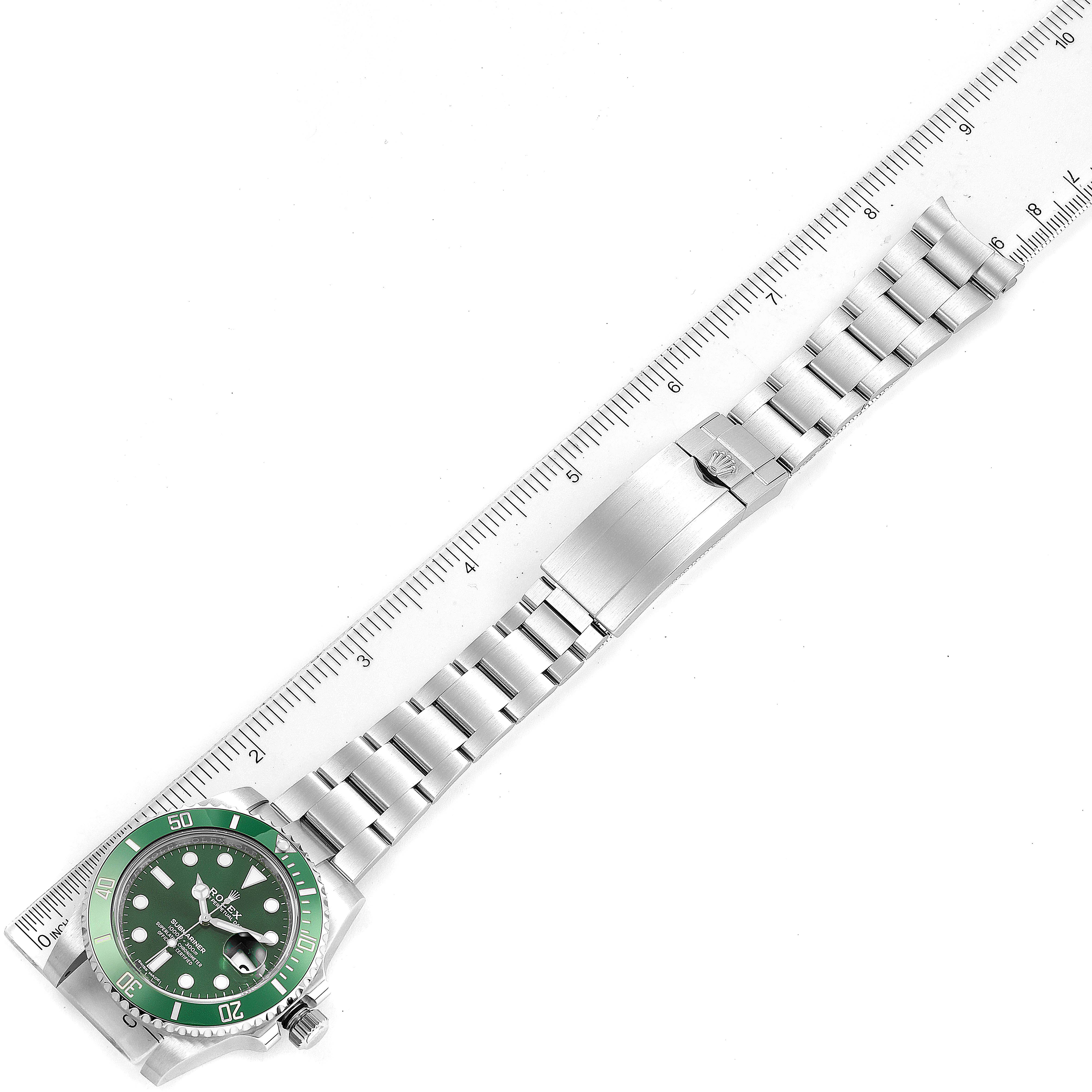 The image shows a Rolex Submariner 116610LV Men
s Stainless Steel Green Dial 116610LV Men
s Stainless Steel Green Dial watch laying flat with a full view of its bracelet linked beside a ruler for size reference.
