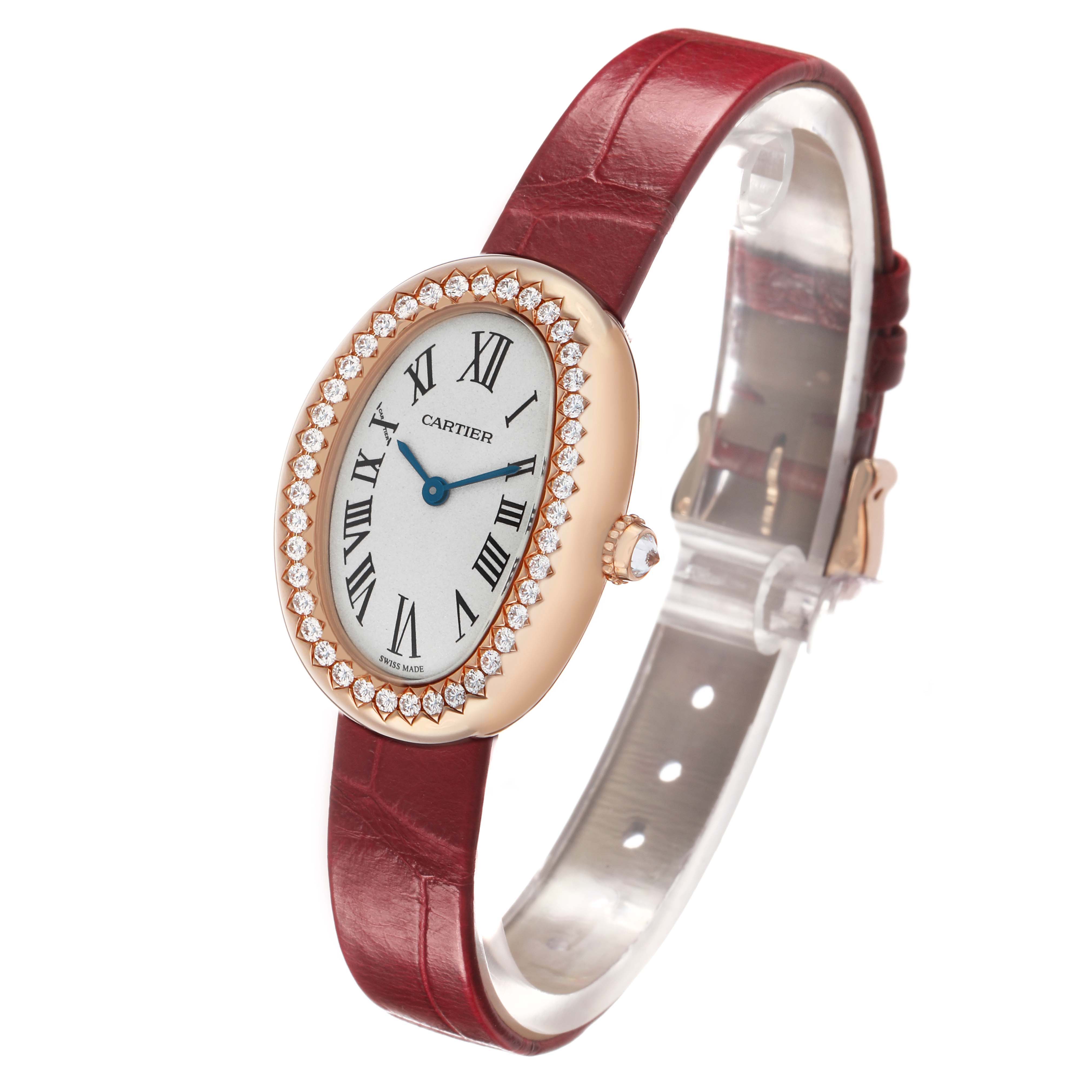 The Cartier Baignoire WJBA0031 Women's Rose Gold Silver Dial watch is shown at an angled view, highlighting its oval face, diamond bezel, and red leather strap.