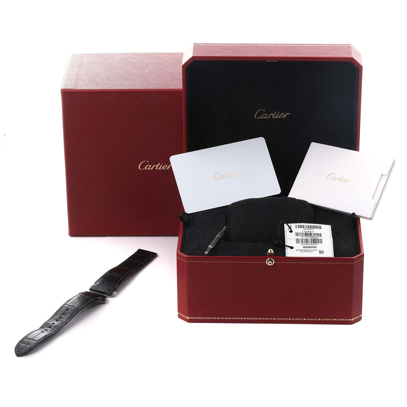 The image shows a Cartier Santos WSSA0039 Men
s Stainless Steel Black Dial WSSA0039 Men
s Stainless Steel Black Dial watch box, cards, a strap, and a tool viewed from above.