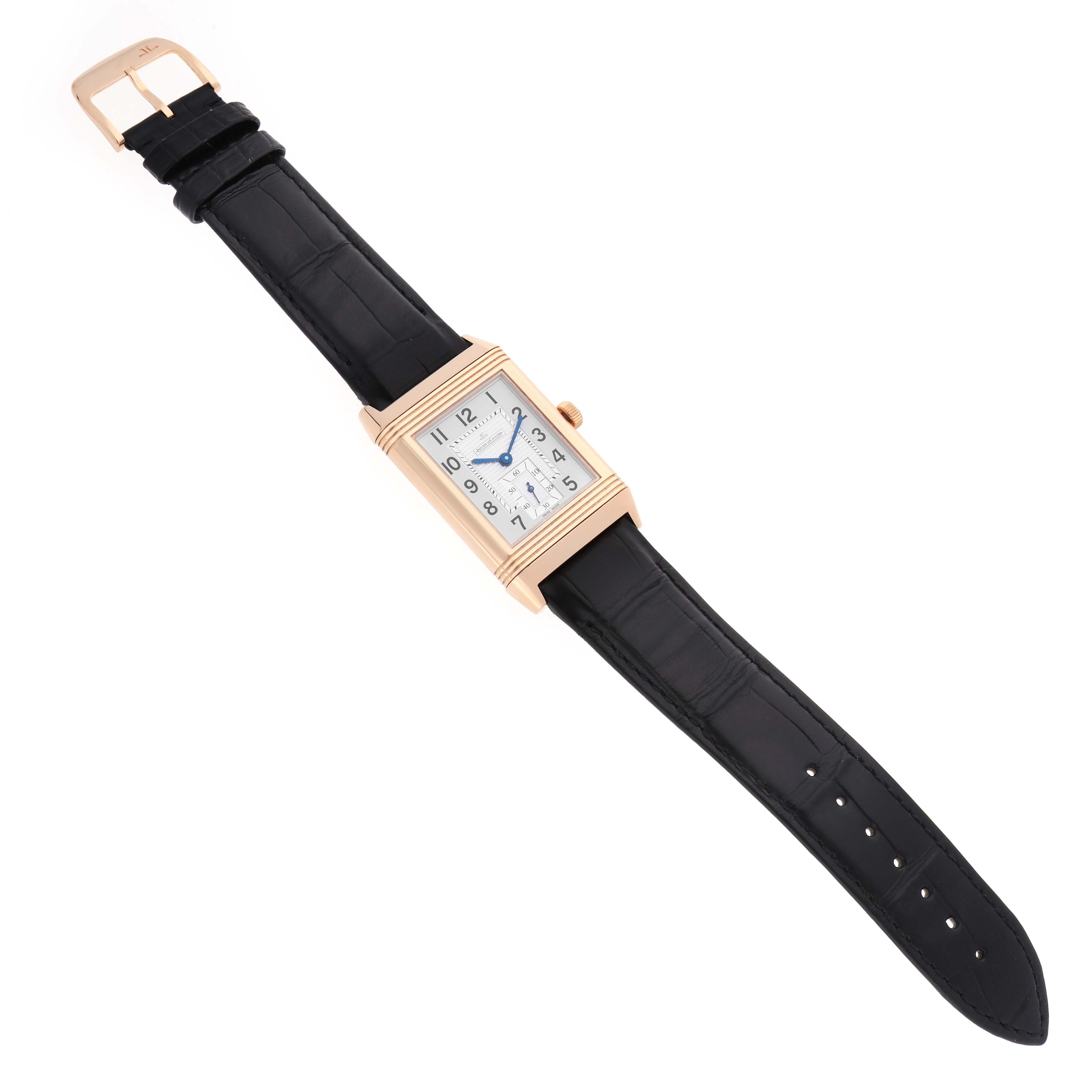 The Jaeger-LeCoultre Reverso watch is shown in a top-down angle, displaying the face, case, buckle, and leather strap.