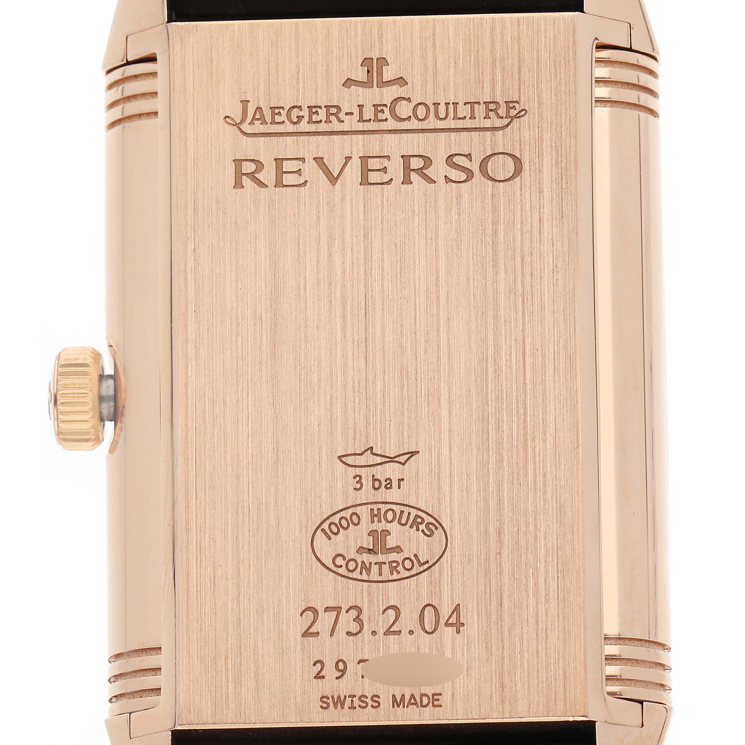 The image shows the back of the Jaeger-LeCoultre Reverso watch, featuring the branding, model details, and crown.