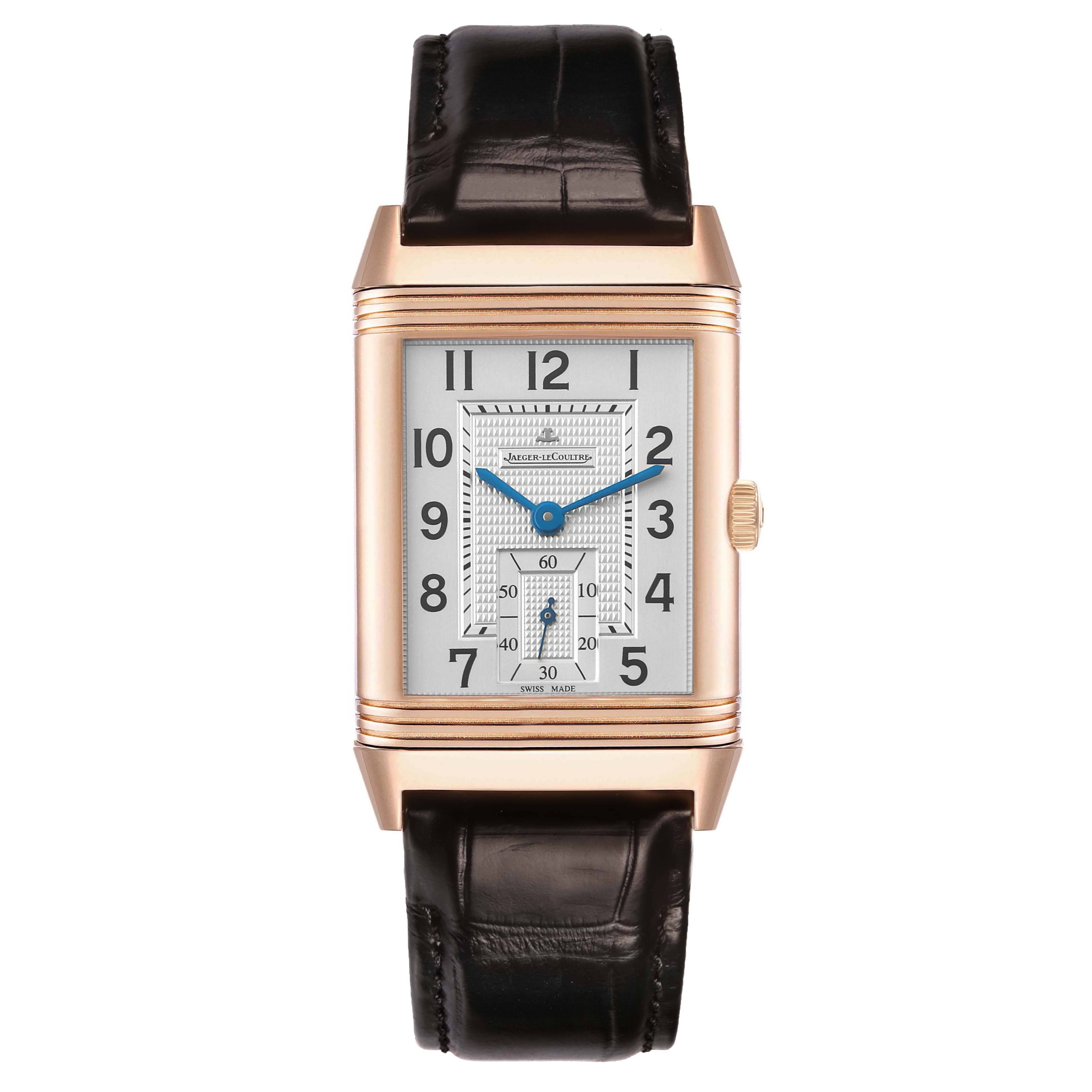 The Jaeger-LeCoultre Reverso watch is shown from a frontal angle, displaying the dial, hands, and leather strap.