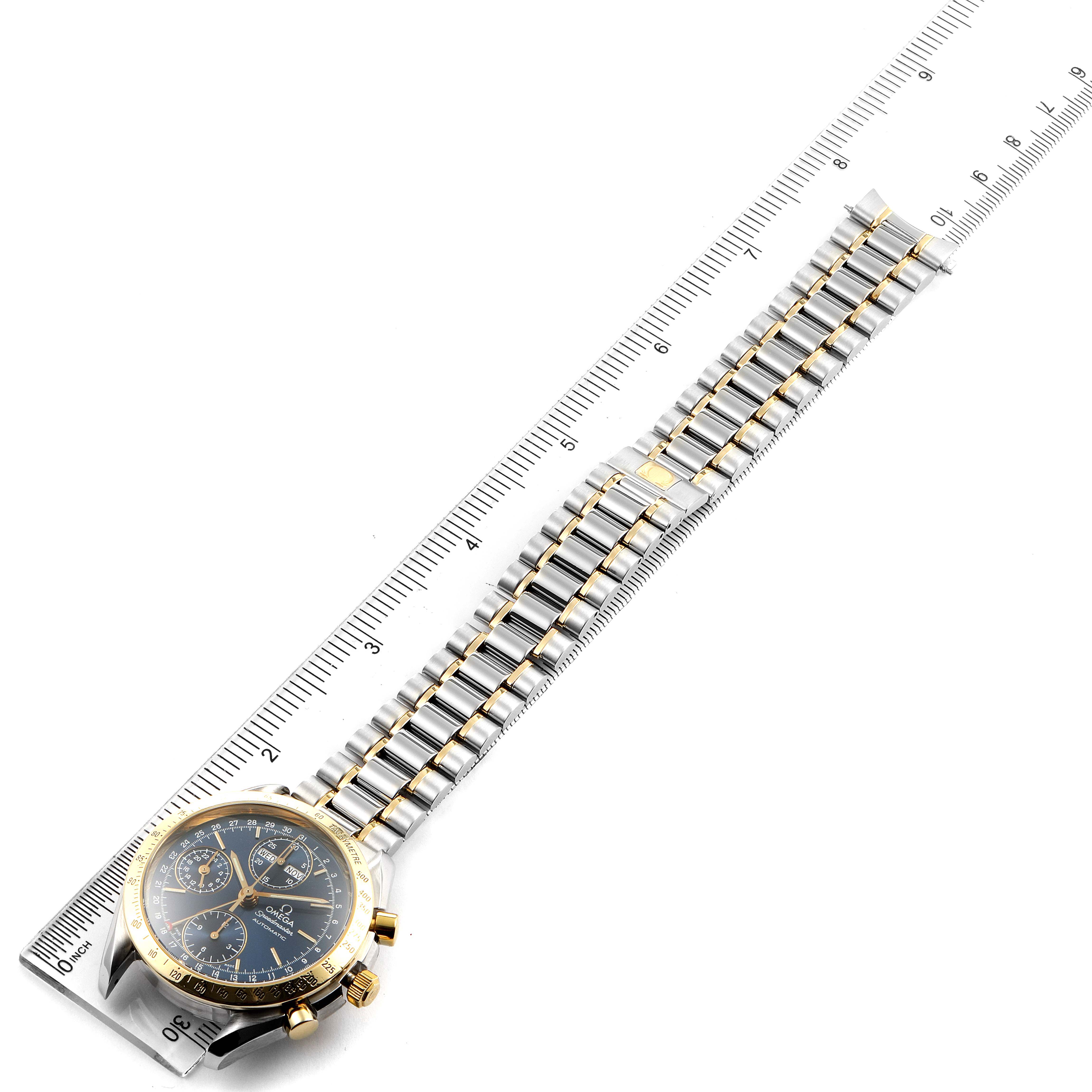 The image shows an Omega Speedmaster 3321.80.00 Men's Steel and Gold (two tone) Blue Dial 3321.80.00 Men's Steel and Gold (two tone) Blue Dial watch laid flat along a ruler, displaying the face and the full length of the metal bracelet.