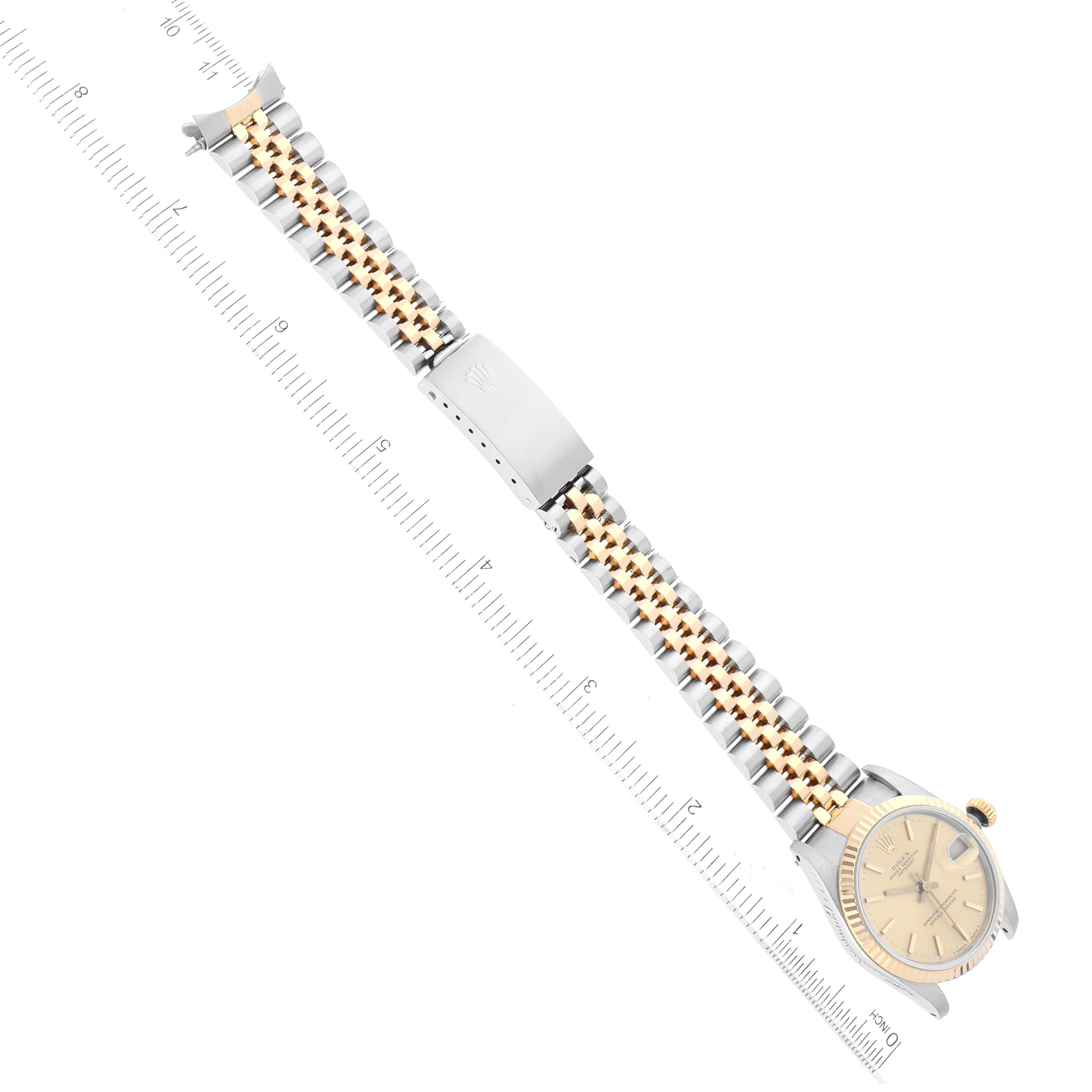The image shows a top-down view of a Rolex Mid-Size 68273 Women
s Steel and Gold (two tone) Champagne Dial 68273 Women
s Steel and Gold (two tone) Champagne Dial model watch with a two-tone metal band and a ruler for scale.