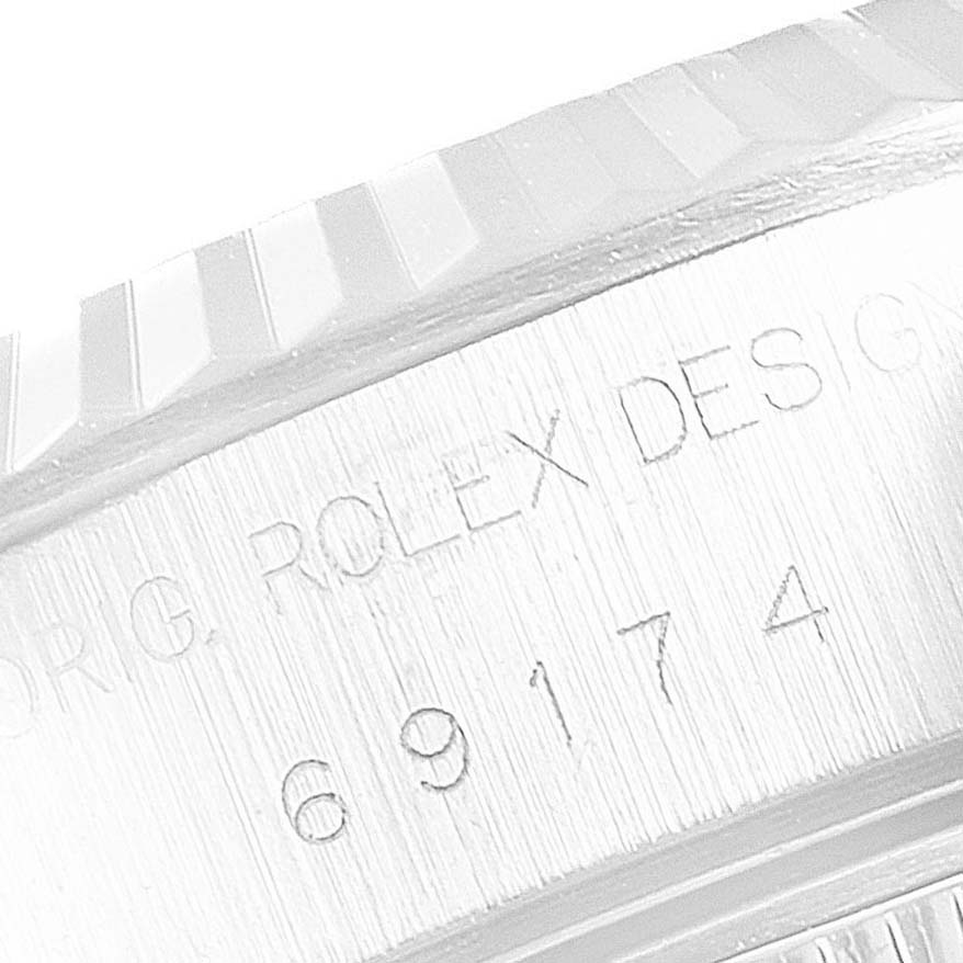 The image focuses on the engraved fluted bezel and case of a Rolex Datejust 69174 Women's Stainless Steel Mother of Pearl Dial 69174 Women's Stainless Steel Mother of Pearl Dial, showing part of the serial and model number.