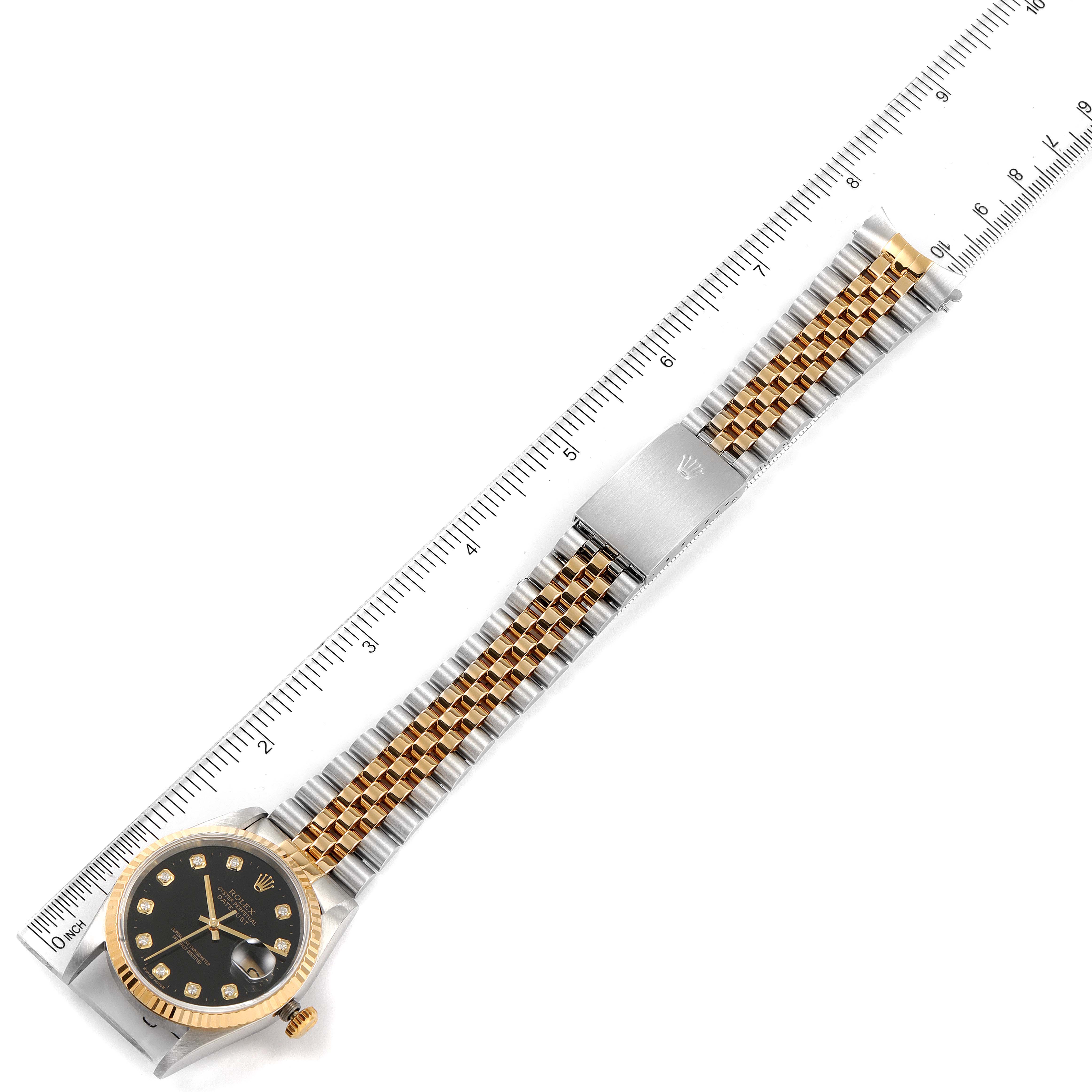 The image shows a top view of a Rolex Datejust 16233 Men's Steel and Gold (two tone) Black Dial 16233 Men's Steel and Gold (two tone) Black Dial watch with its gold and silver bracelet fully extended alongside a ruler.