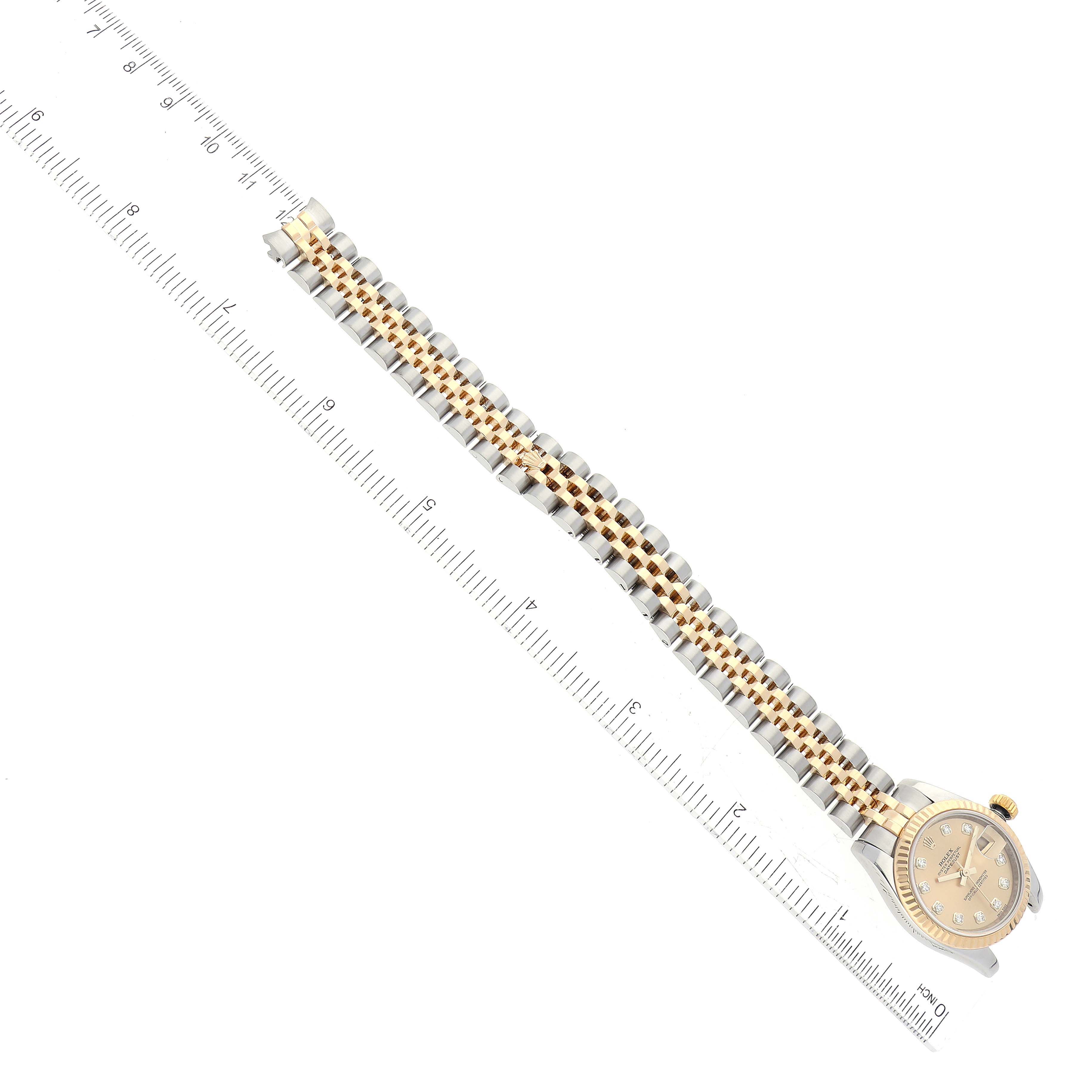 The image shows a top-down view of a Rolex Datejust 179173G Women's Steel and Gold (two tone) Champagne Dial 179173G Women's Steel and Gold (two tone) Champagne Dial watch, highlighting the entire band and partial face next to a ruler.