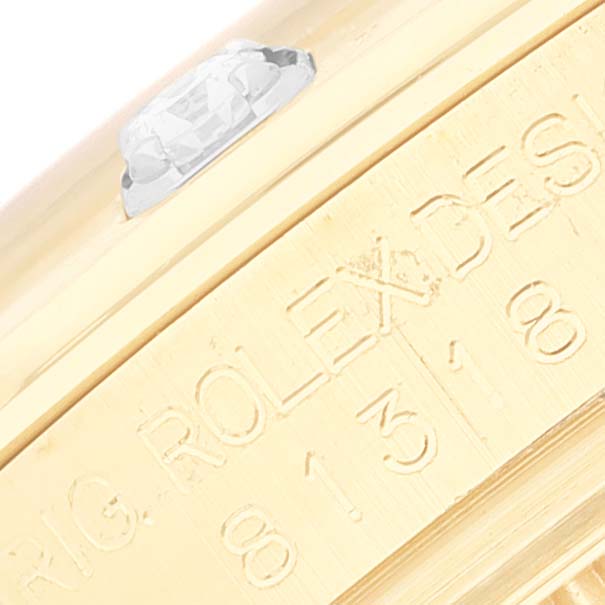 The image shows a close-up of the side of a Rolex Pearlmaster 81318 Women's Yellow Gold Mother of Pearl Dial 81318 Women's Yellow Gold Mother of Pearl Dial watch, focusing on the engraved model details and a part of the bezel with a diamond.