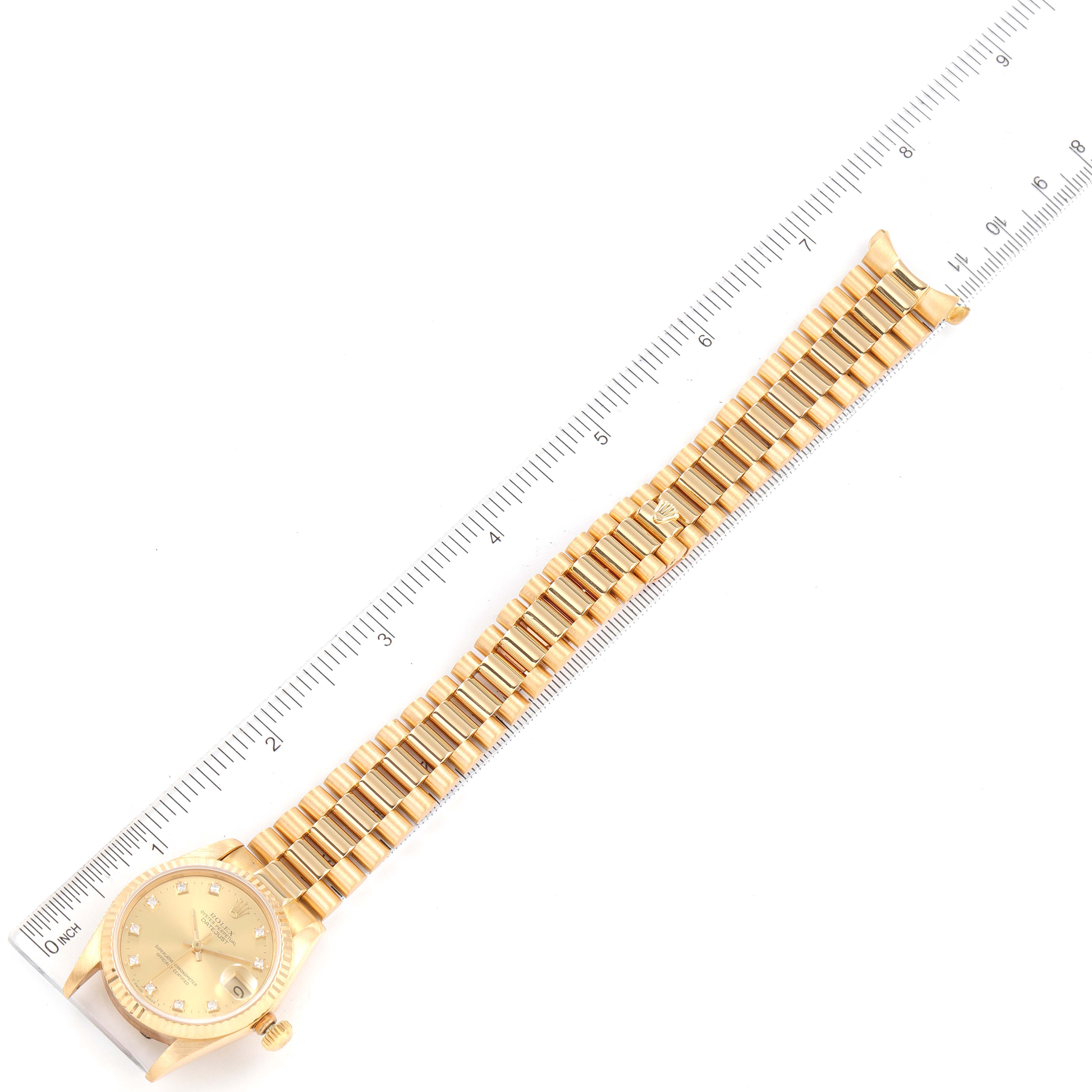 The image shows a top-down view of a Rolex President 38706 Women
s Yellow Gold Champagne Dial 38706 Women
s Yellow Gold Champagne Dial model watch, including the face, bracelet, and a ruler for scale.