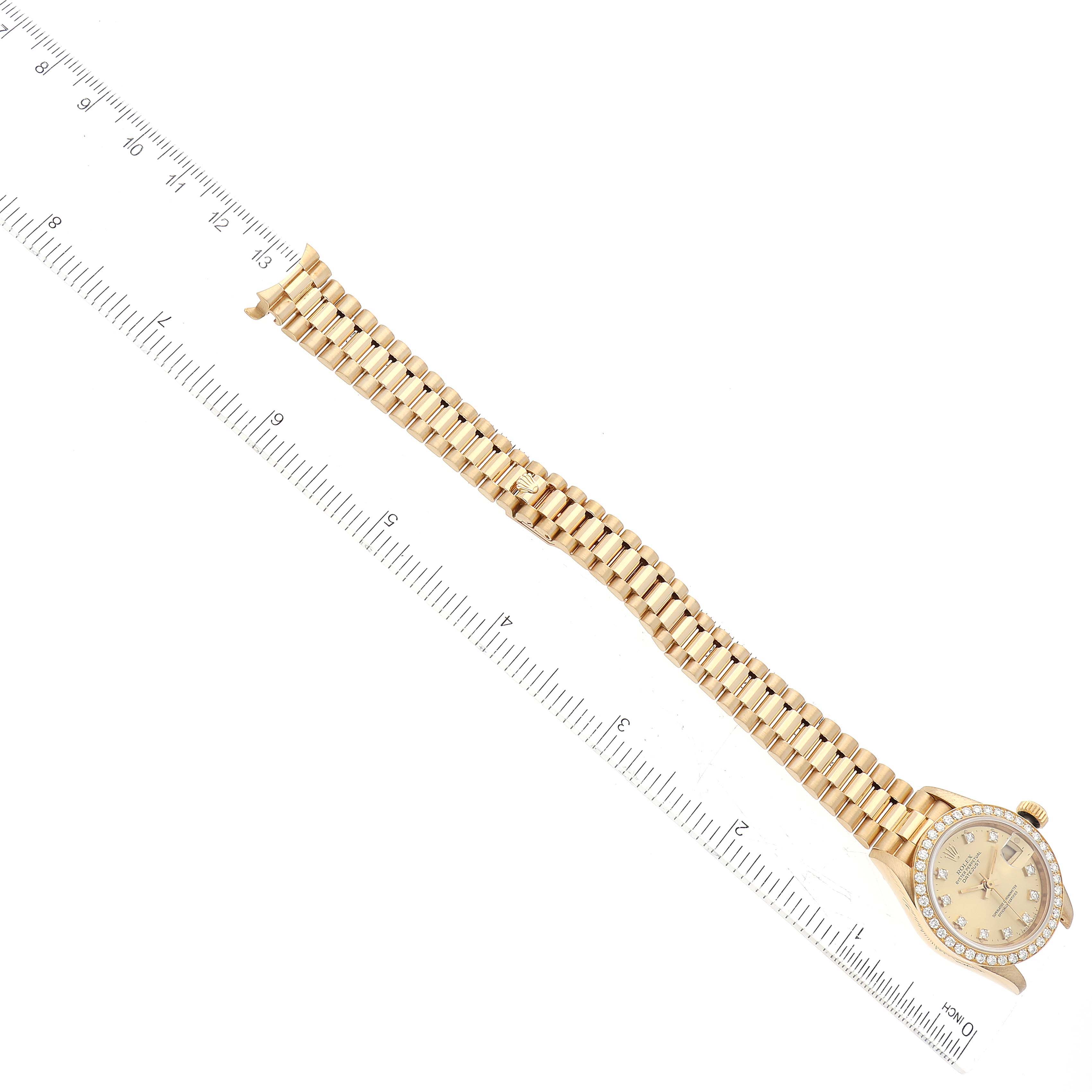 The Rolex President 69138G Women
s Yellow Gold Champagne Dial 69138G Women
s Yellow Gold Champagne Dial model watch is shown from a top-down angle, with the full band and dial visible next to a ruler for scale.
