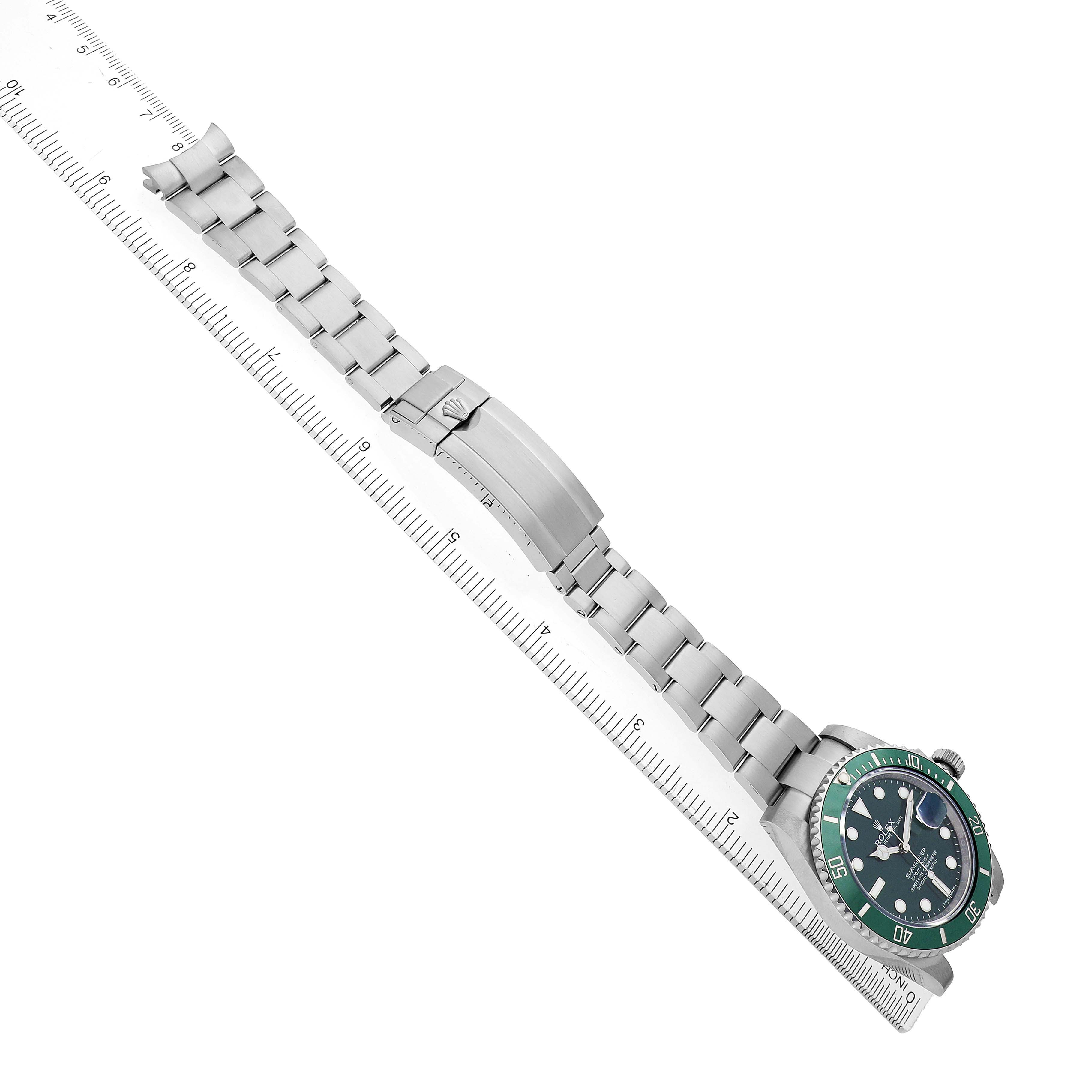 The Rolex Submariner 116610LV Men's Stainless Steel Green Dial watch is shown diagonally with its bracelet fully extended alongside a ruler.