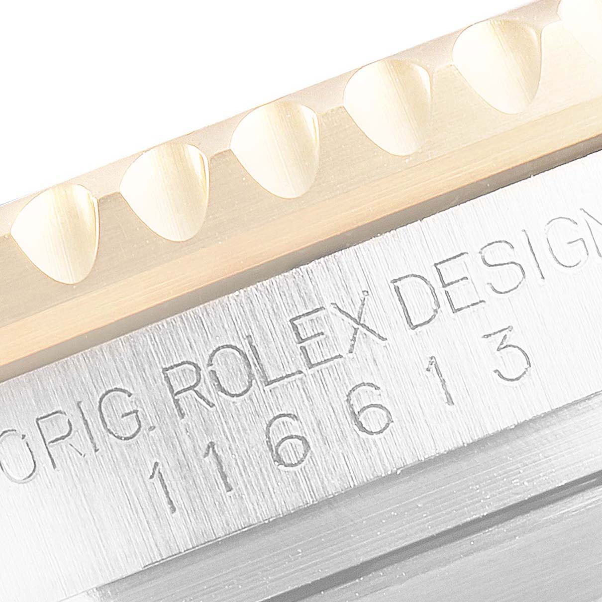 This close-up image shows the serrated edge and "Orig. Rolex Design 116613" engraving on the bezel and case of a Rolex Submariner 116613 Men's Steel and Gold (two tone) Blue Dial 116613 Men's Steel and Gold (two tone) Blue Dial.
