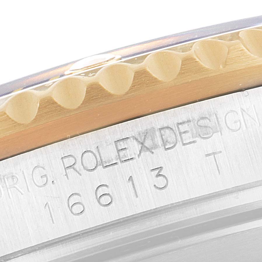 The image shows an angled, close-up view of the bezel and engraved case of a Rolex Submariner 16613 Men's Steel and Gold (two tone) Grey Dial 16613 Men's Steel and Gold (two tone) Grey Dial model 16613 watch.