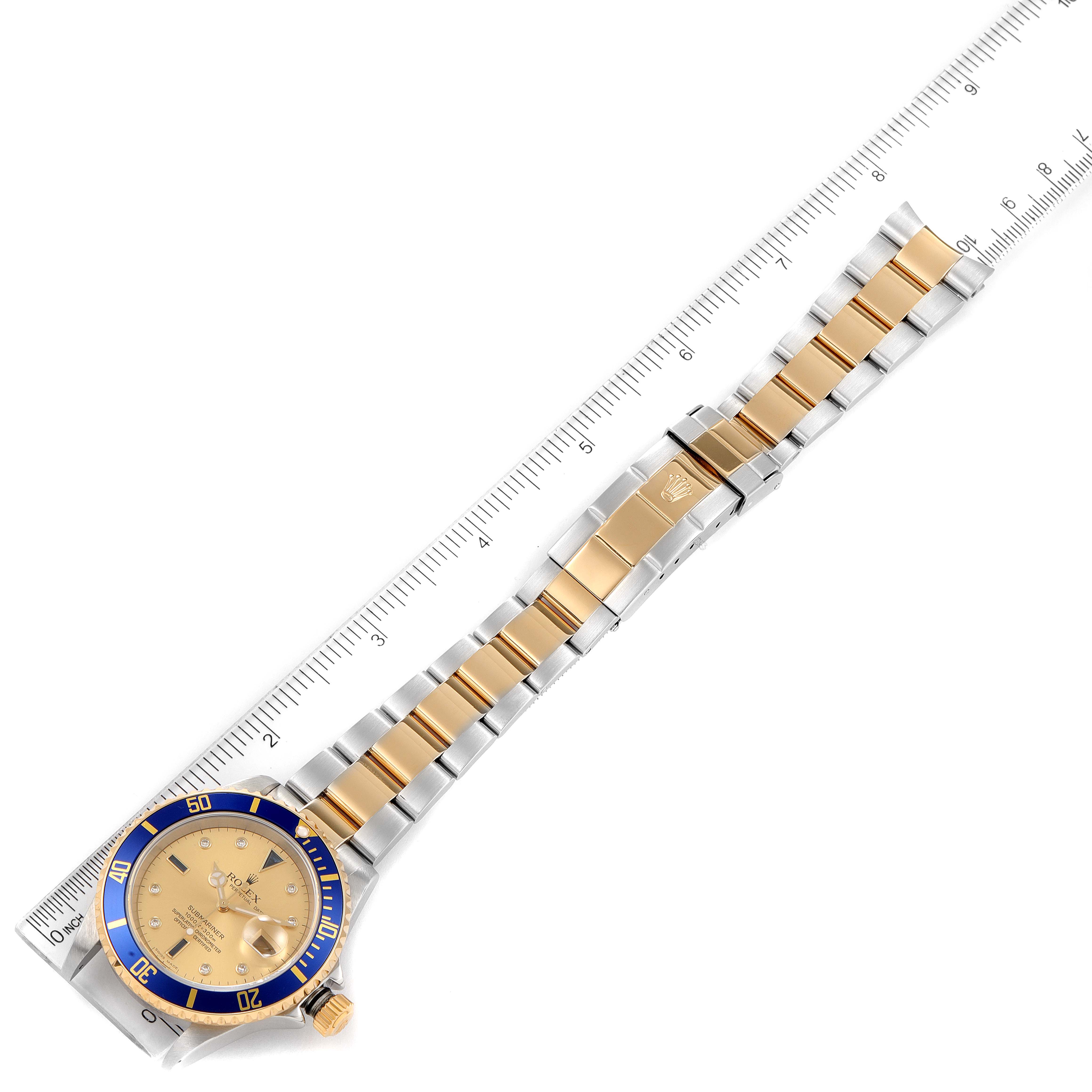 The image shows a Rolex Submariner 16613 Men's Steel and Gold (two tone) Champagne Dial 16613 Men's Steel and Gold (two tone) Champagne Dial watch from an overhead angle, including the full bracelet and a ruler for scale.