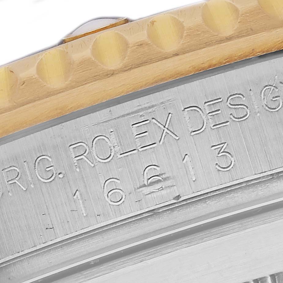 The image shows a close-up of the edge of the Rolex Submariner 16613SG Men's Steel and Gold (two tone) Silver Dial 16613SG Men's Steel and Gold (two tone) Silver Dial bezel, focusing on the engraved model number.
