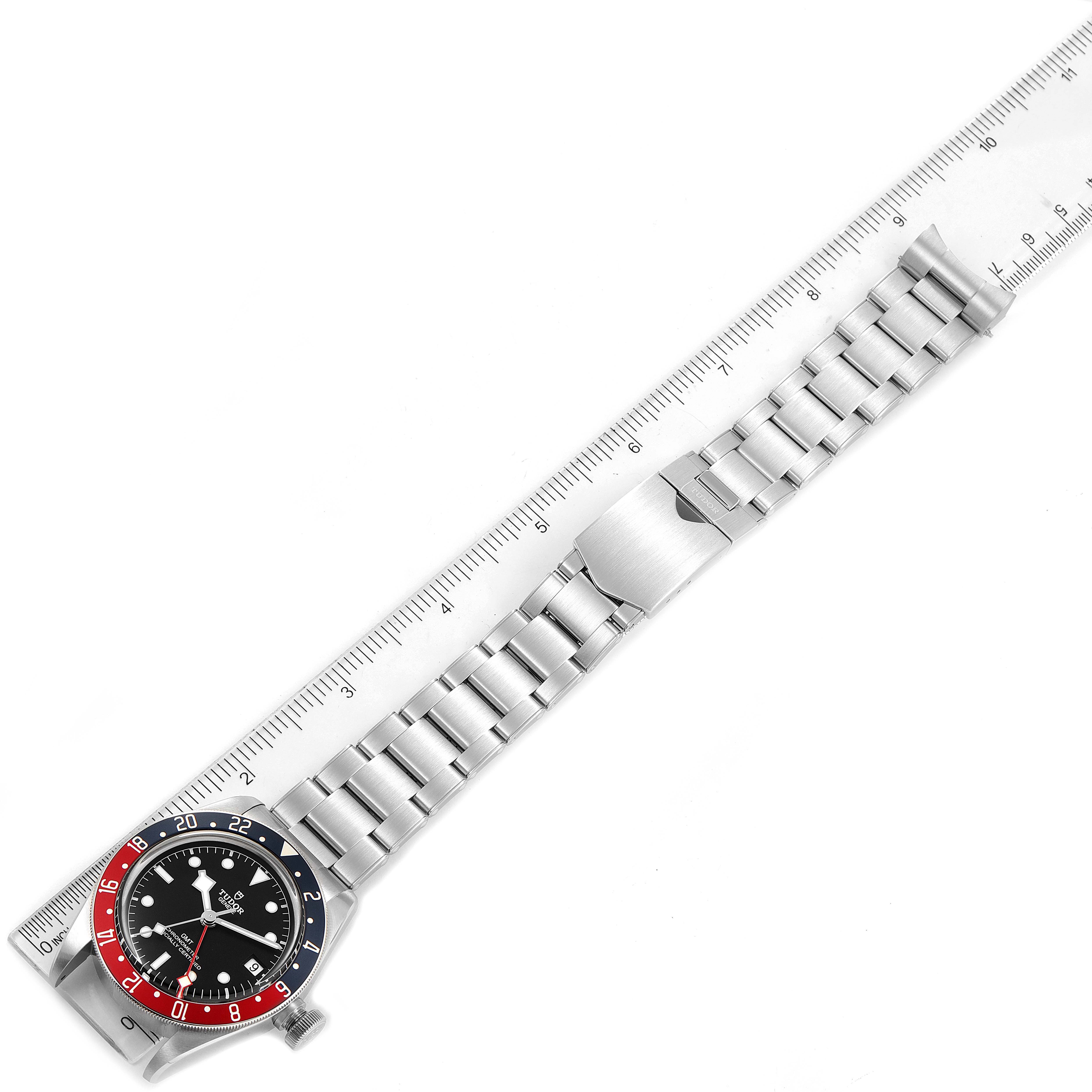 The image shows a top-down view of a Tudor Heritage Black Bay 79830RB Men's Stainless Steel Black Dial 79830RB Men's Stainless Steel Black Dial watch with a metal bracelet laid beside a ruler.