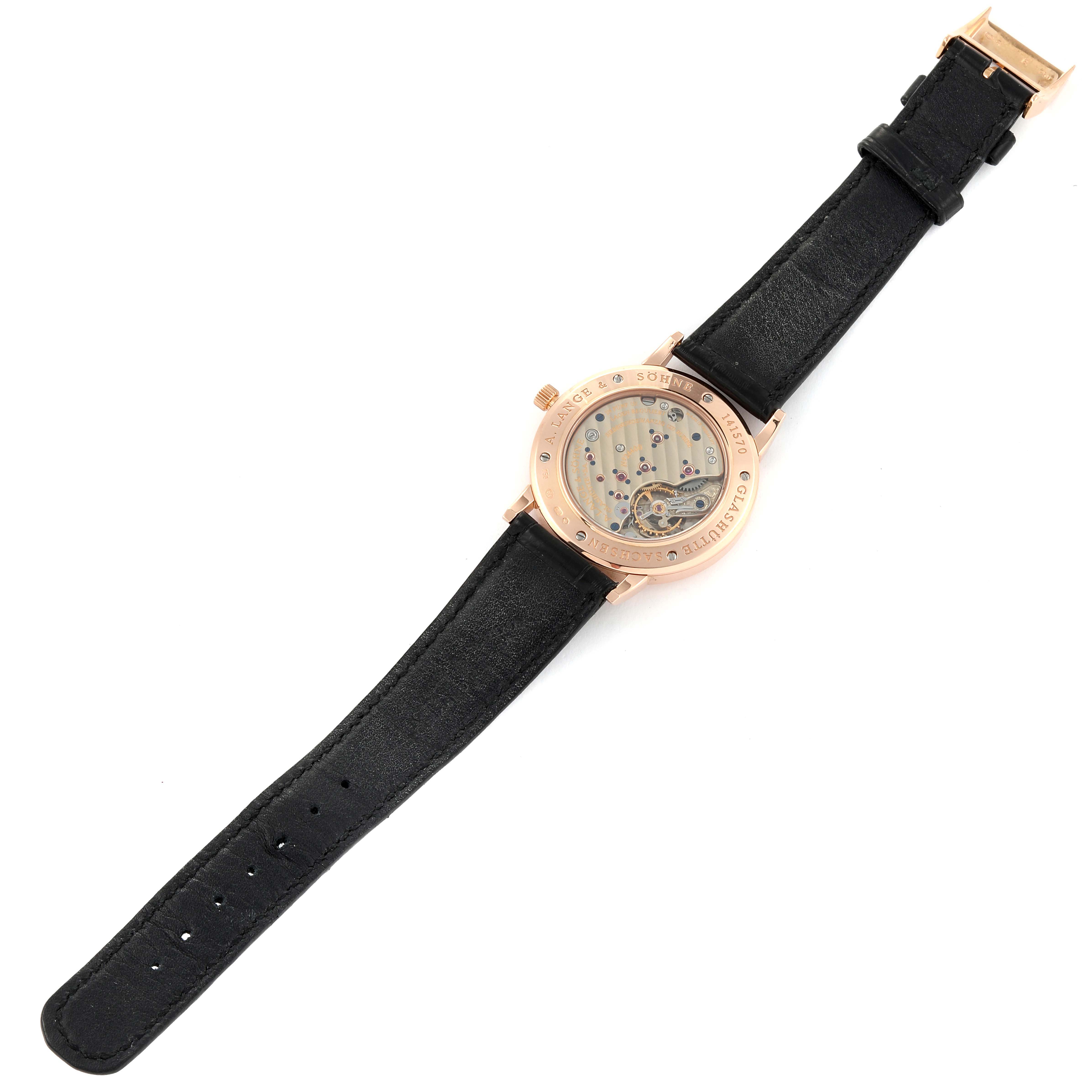 The image shows the back view of the A. Lange & Sohne 1815 221.032 Men's Rose Gold Silver Dial model watch, highlighting its movement and black strap.