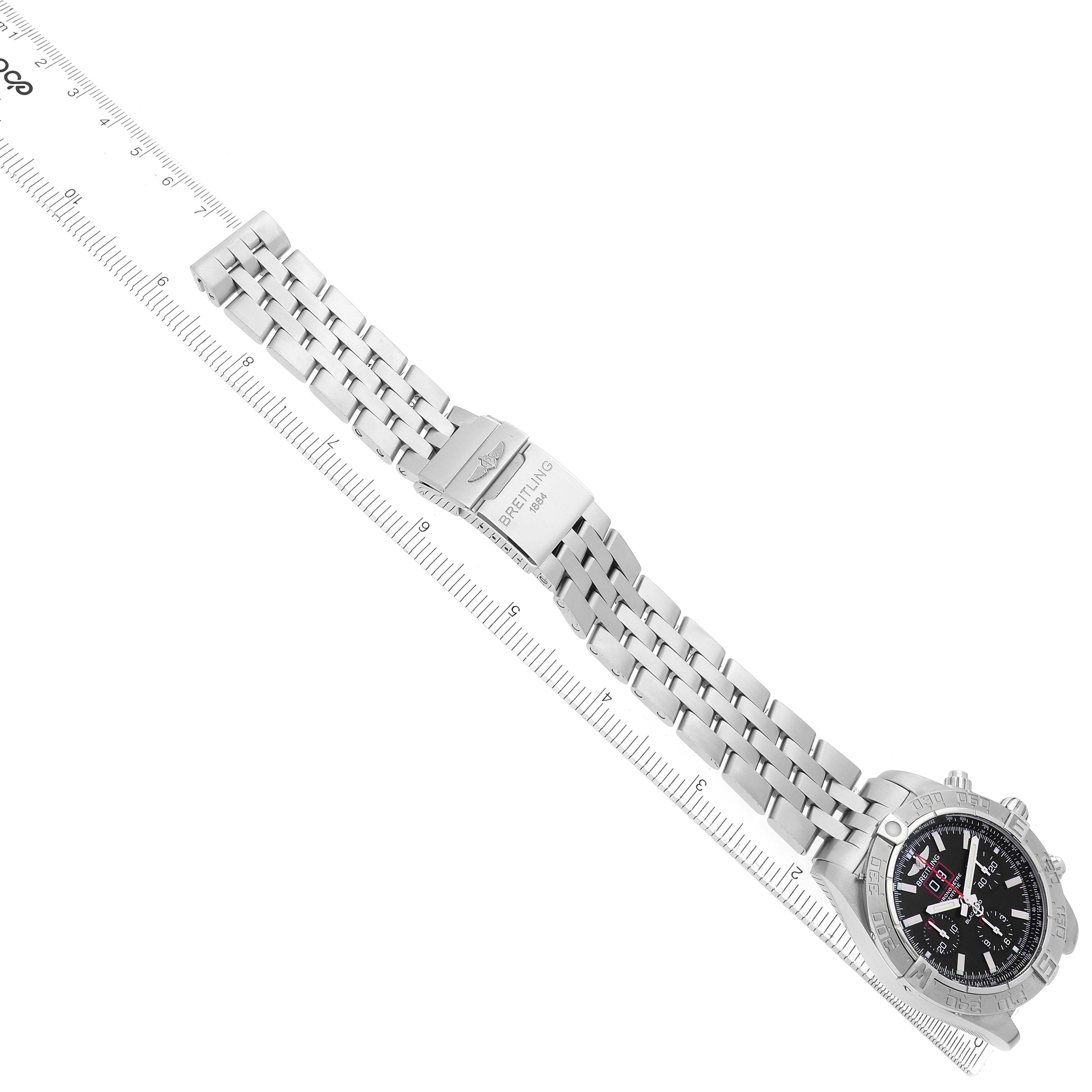 The Breitling Chronomat A44360 Men's Stainless Steel Black Dial watch is shown diagonally with the bracelet and clasp visible, alongside a ruler for scale.