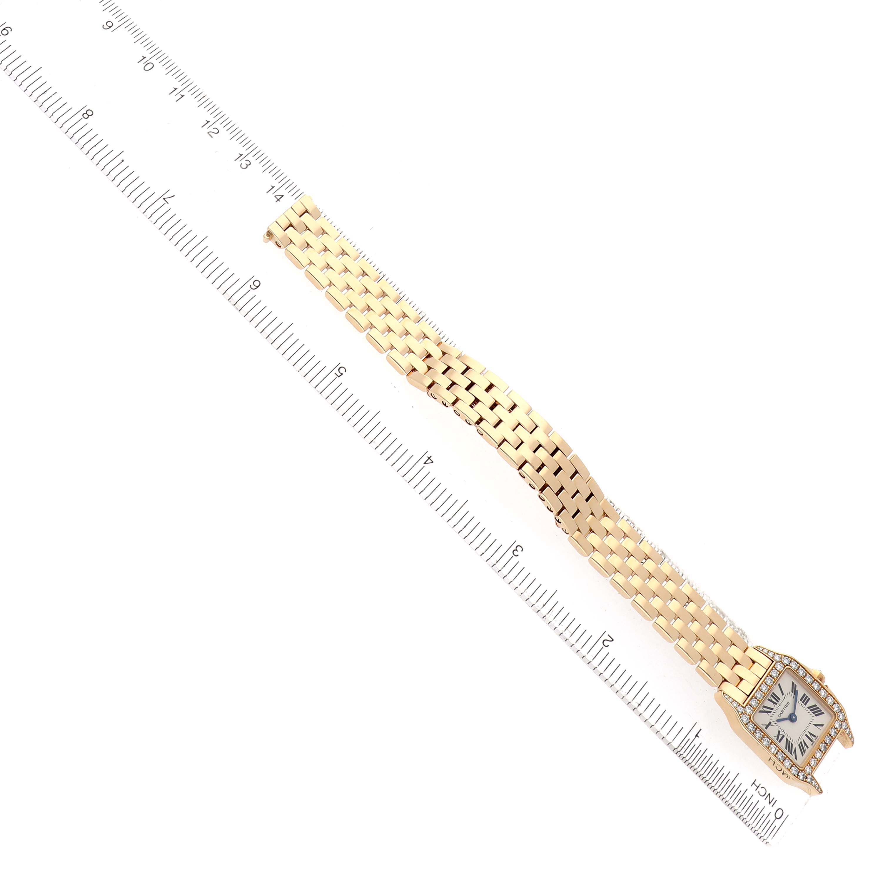 The Santos Demoiselle by Cartier is shown at an angle, displaying its face and full linked bracelet alongside a ruler.