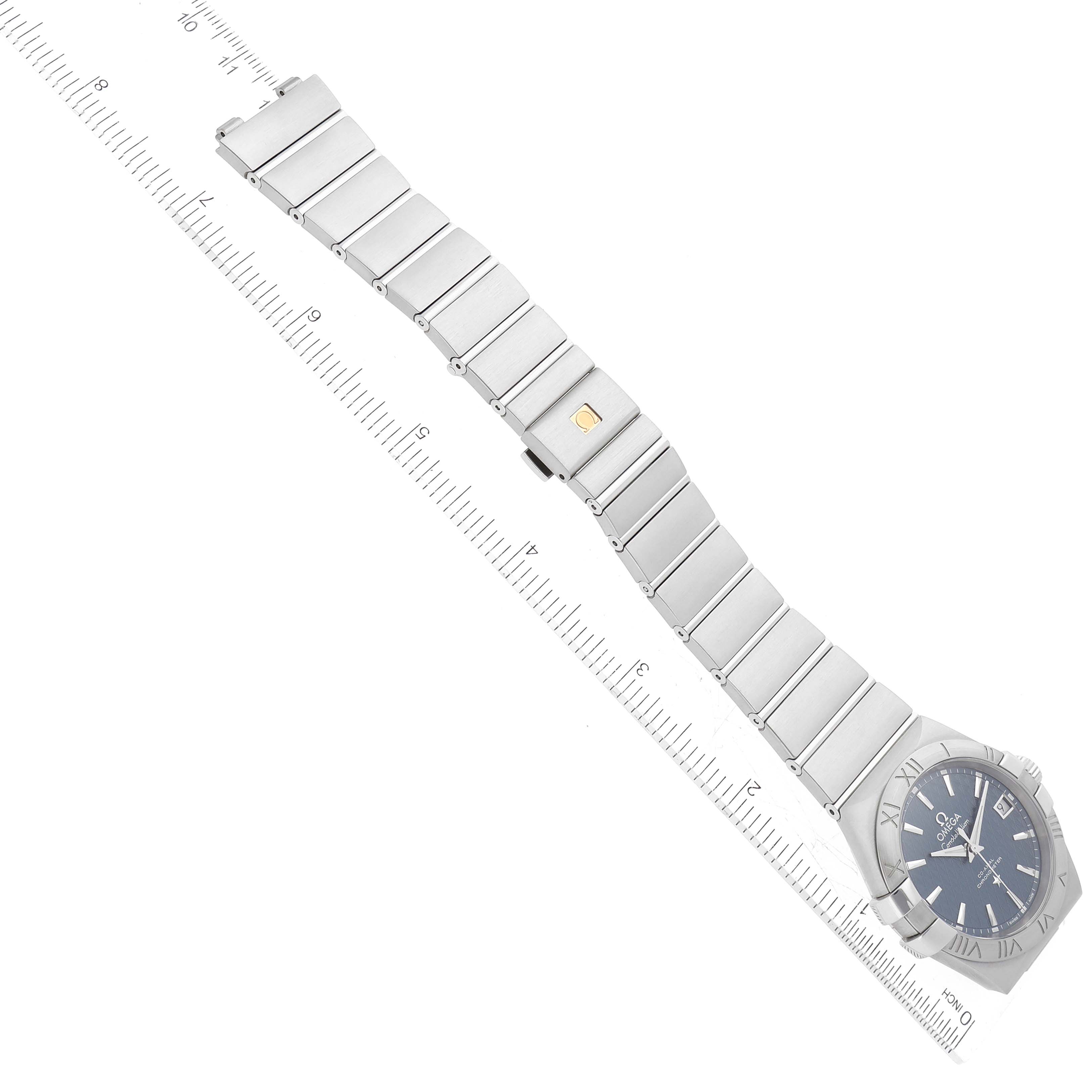 The image shows an Omega Constellation 123.10.35.20.03.002 Men's Stainless Steel Blue Dial 123.10.35.20.03.002 Men's Stainless Steel Blue Dial watch laid flat with its stainless steel bracelet fully extended and positioned alongside a ruler for sizing.