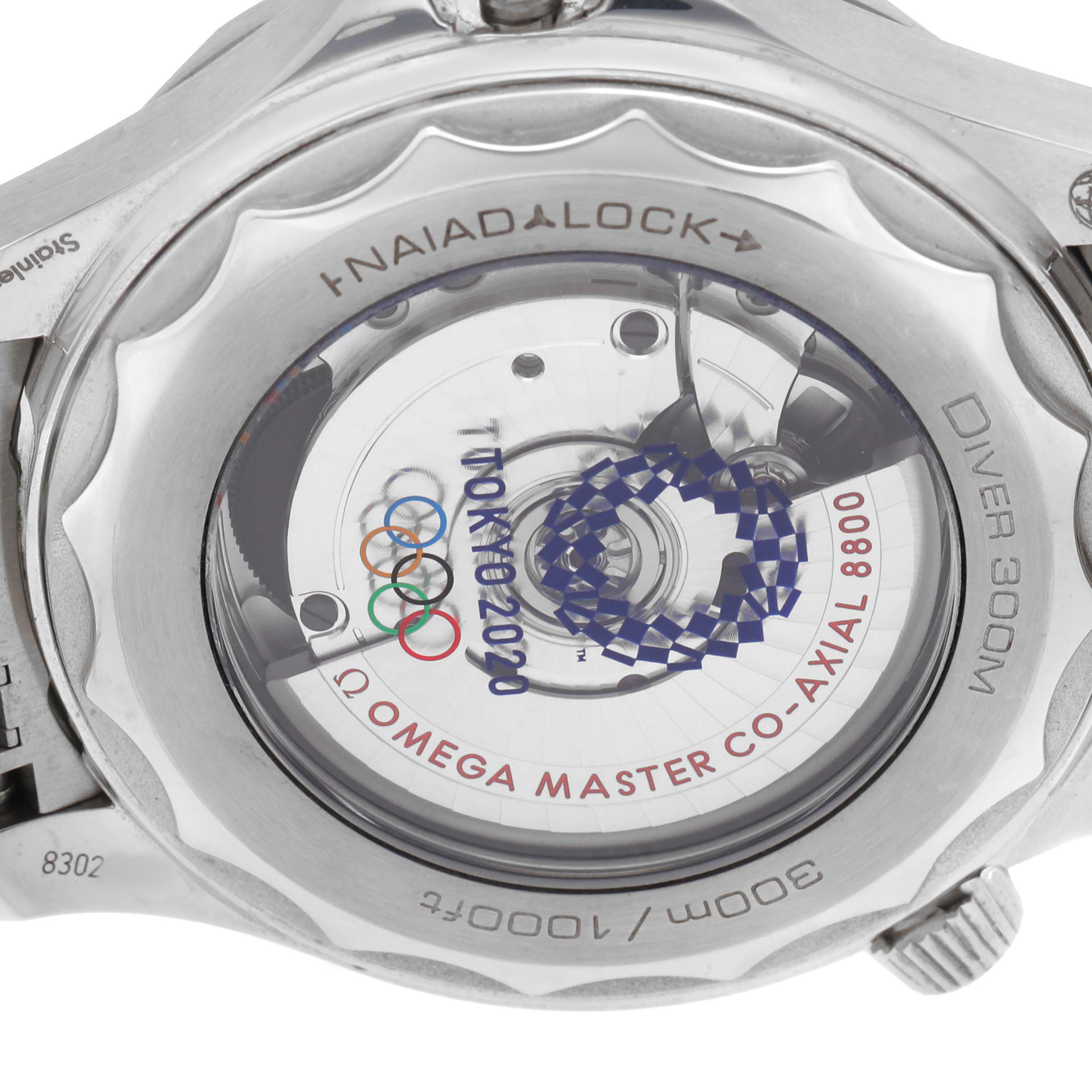 The image shows the back of an Omega Seamaster 522.30.42.20.04.001 Men's Stainless Steel White Dial, showcasing the Naiad Lock system and co-axial movement with Tokyo 2020 design.