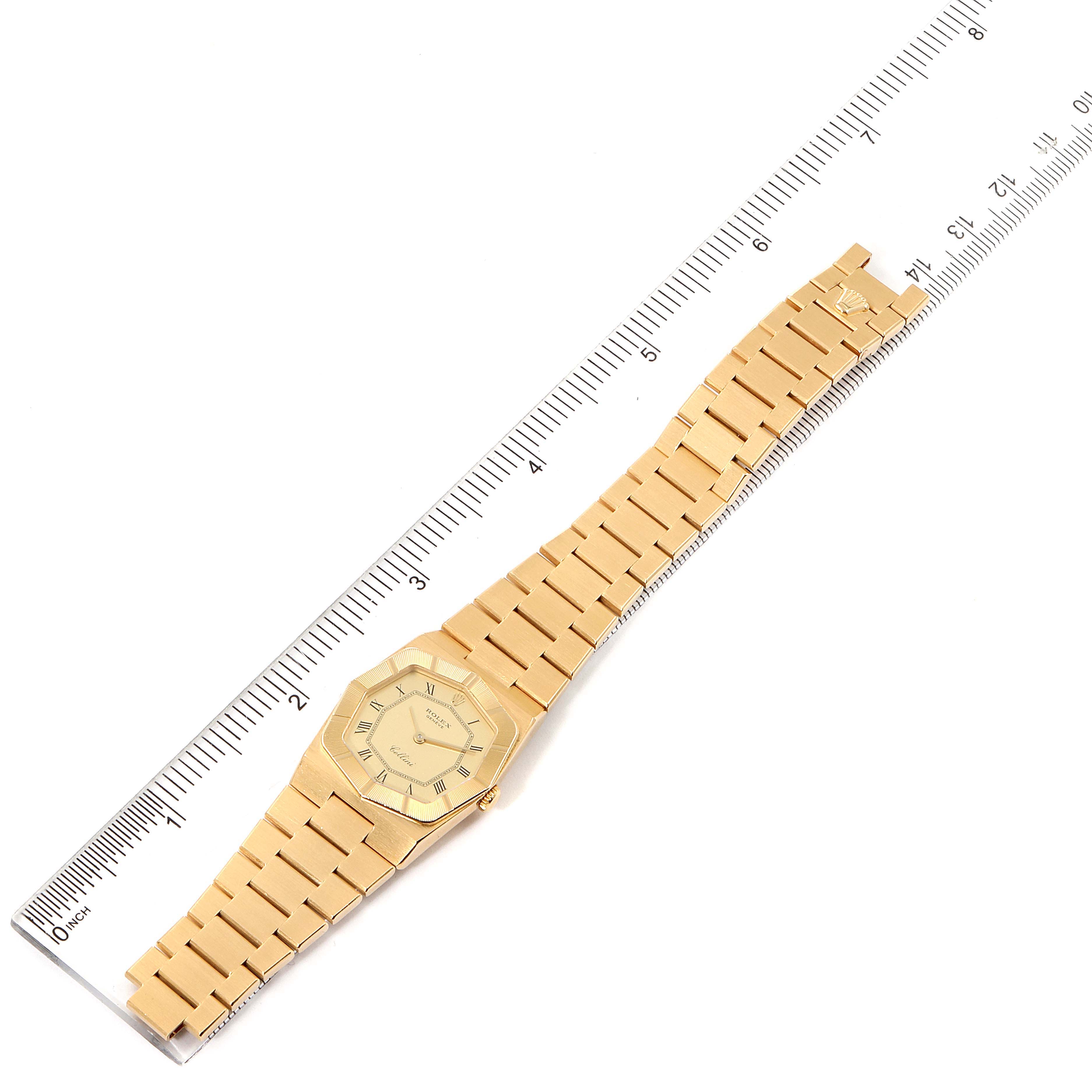 The Rolex Cellini 4360 Women's Yellow Gold Champagne Dial 4360 Women's Yellow Gold Champagne Dial watch is positioned flat and fully extended, lying alongside a ruler for measurement.