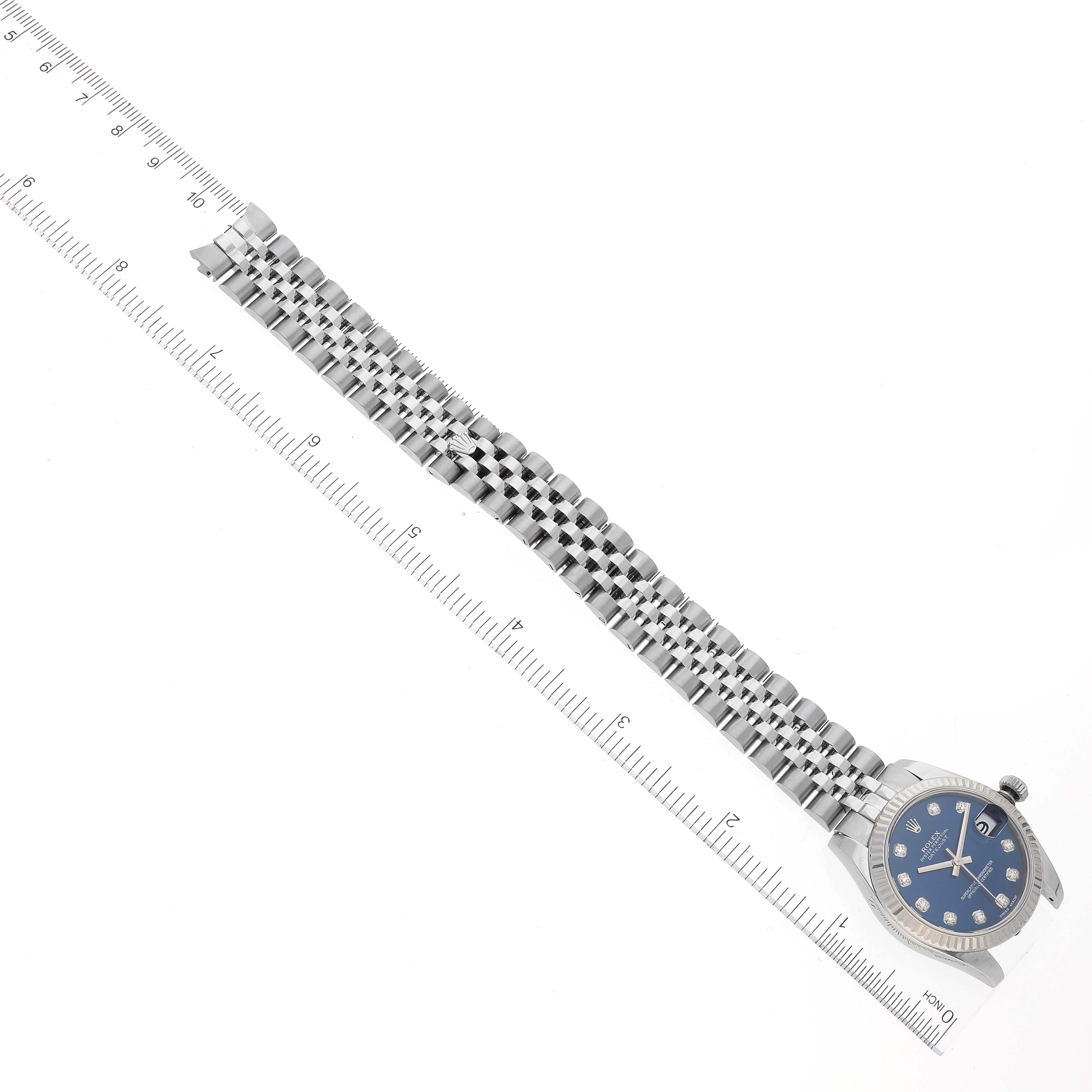 This image shows a Rolex Mid-Size 178274 Women
s Stainless Steel Blue Dial 178274 Women
s Stainless Steel Blue Dial watch laid flat from a top-down angle, highlighting its bracelet, face, and a nearby ruler for scale.