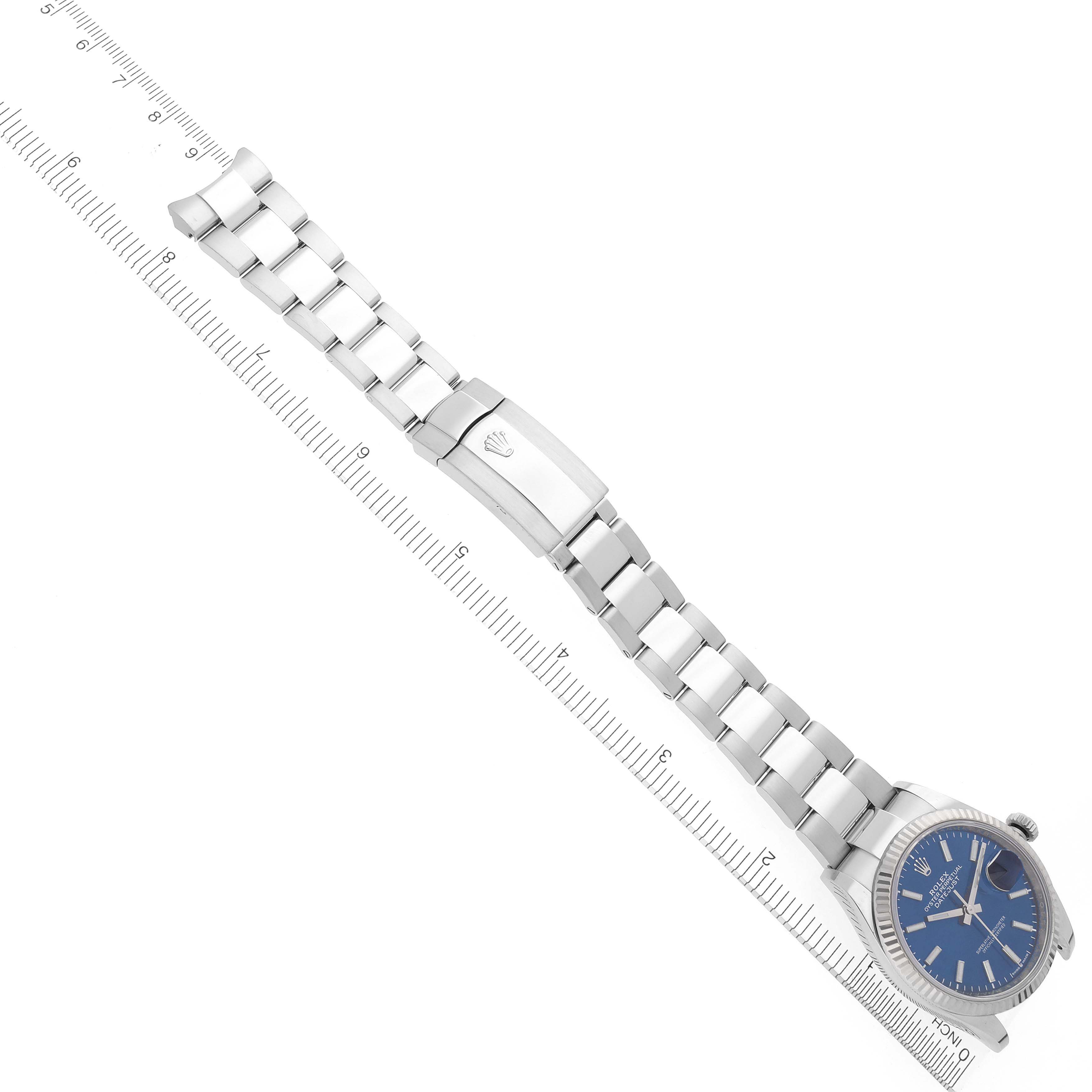 The Rolex Datejust 126234 Men's Stainless Steel Blue Dial 126234 Men's Stainless Steel Blue Dial is shown horizontally with a focus on the bracelet and clasp alongside a ruler for scale.