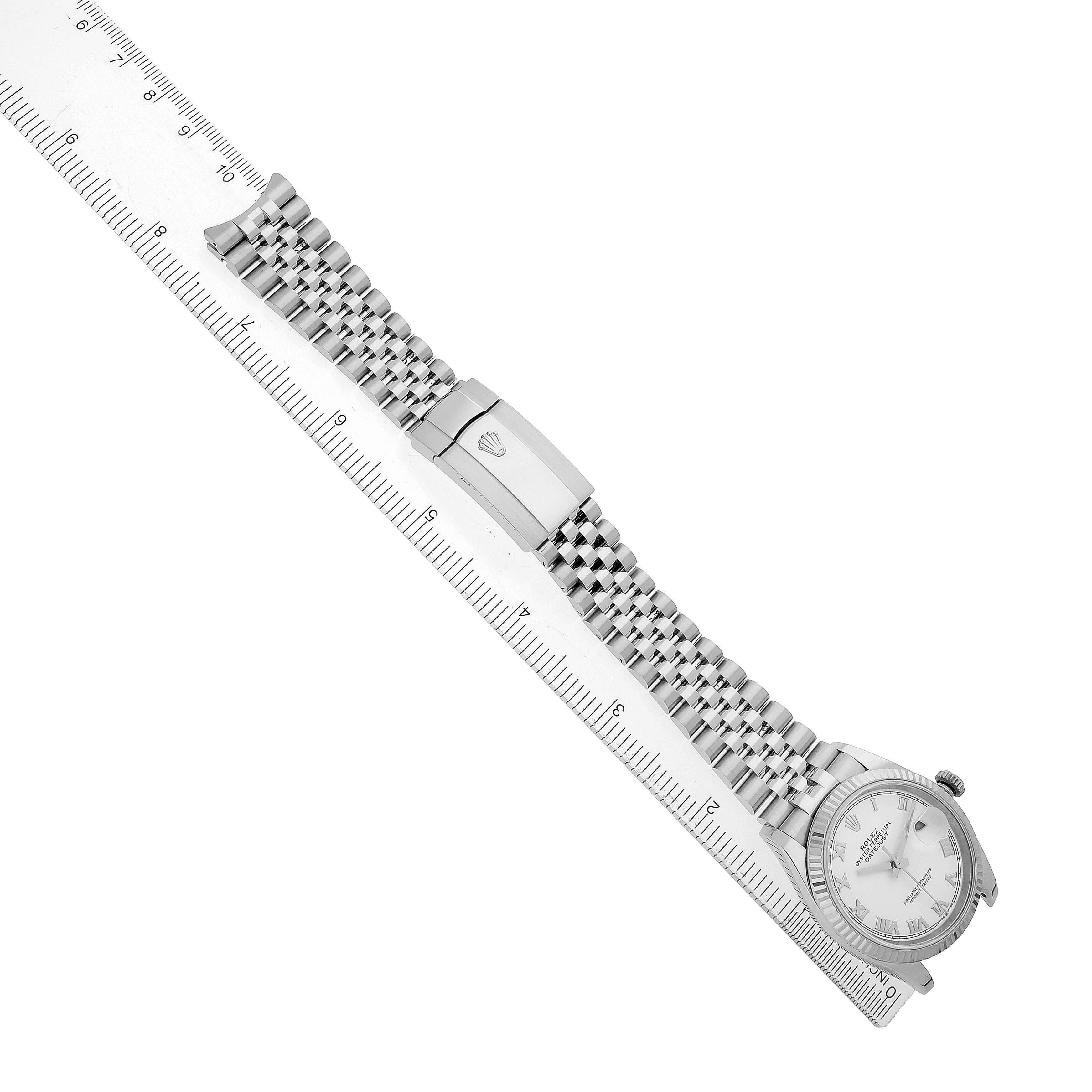 The Rolex Datejust 126234 Men's Stainless Steel White Dial watch is shown lying flat alongside a ruler, with a full view of the bracelet and partially of the watch face.