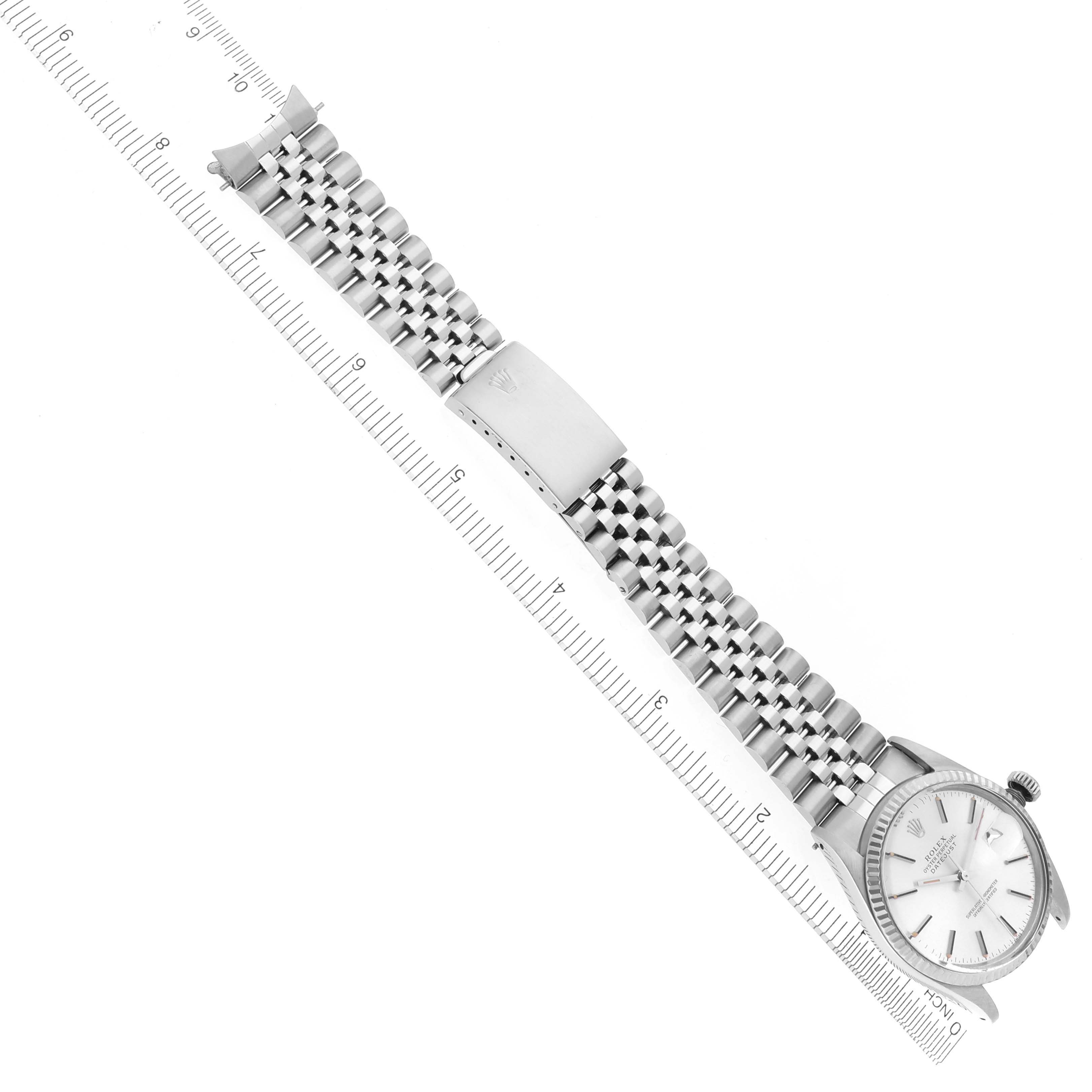 The Rolex Vintage Collection 16014 Men's Stainless Steel Silver Dial 16014 Men's Stainless Steel Silver Dial watch is shown diagonally from a top view, displaying the face, bracelet, and clasp beside a ruler.