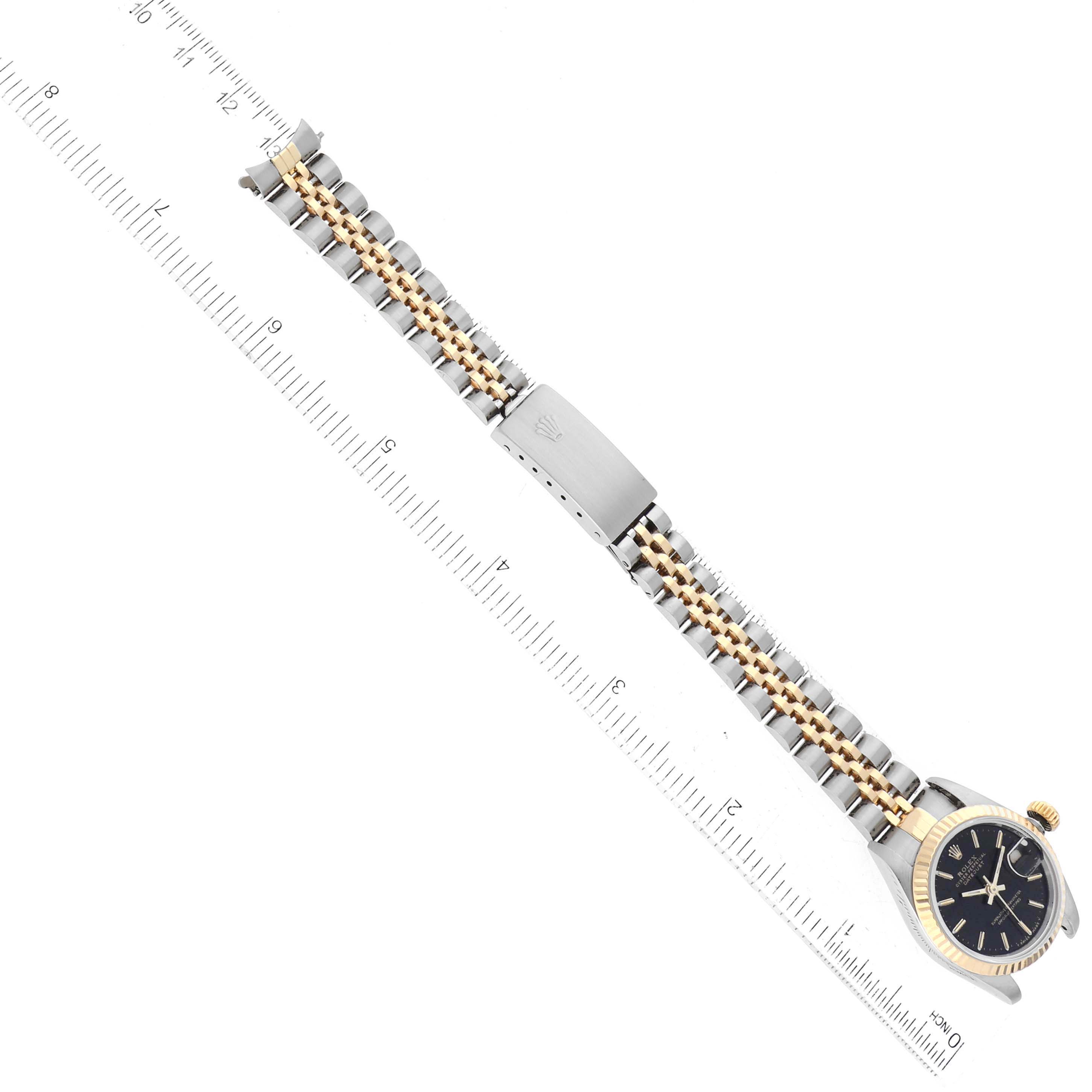 The image shows a Rolex Datejust 69173 Women's Steel and Gold (two tone) Black Dial watch laid flat, showcasing the two-tone bracelet and clasp alongside a measuring ruler.