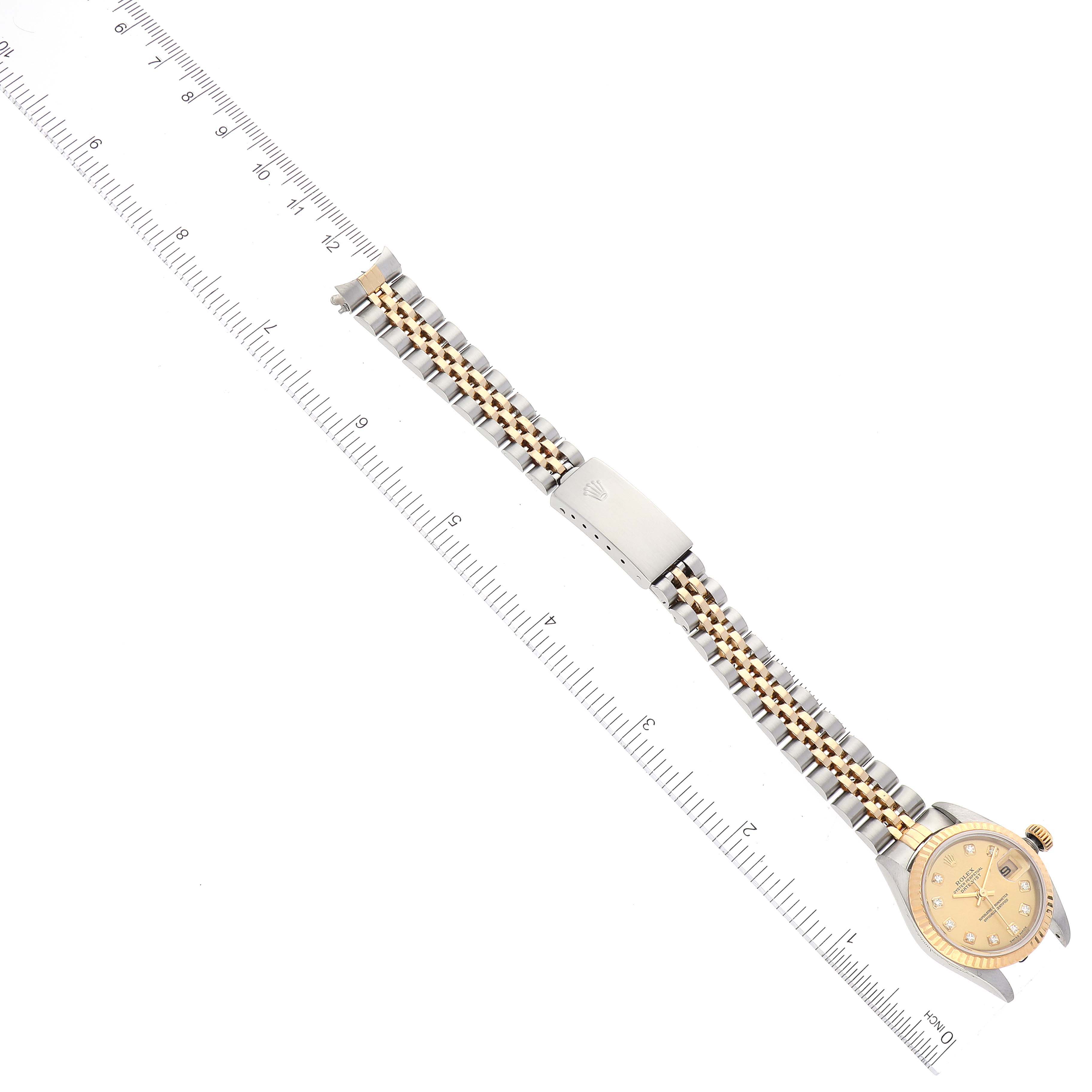 The image shows a Rolex Datejust 79173 Women's Steel and Gold (two tone) Champagne Dial 79173 Women's Steel and Gold (two tone) Champagne Dial watch laid flat, displaying its face, bracelet, and clasp alongside a ruler for scale.