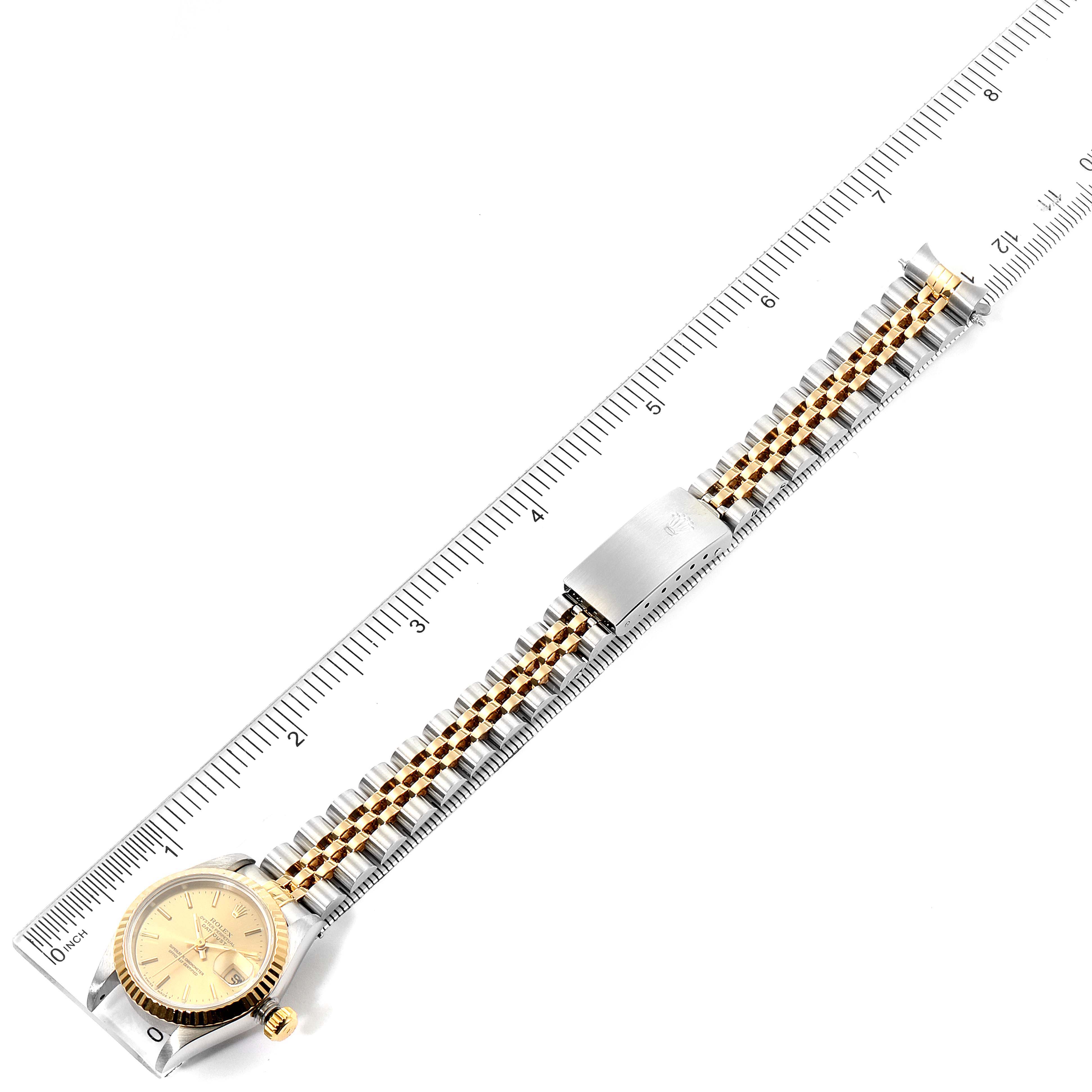 The Rolex Datejust 69173 Women's Steel and Gold (two tone) Champagne Dial 69173 Women's Steel and Gold (two tone) Champagne Dial watch is shown from a top-down angle, displaying its dial, case, bezel, and two-tone bracelet against a ruler.