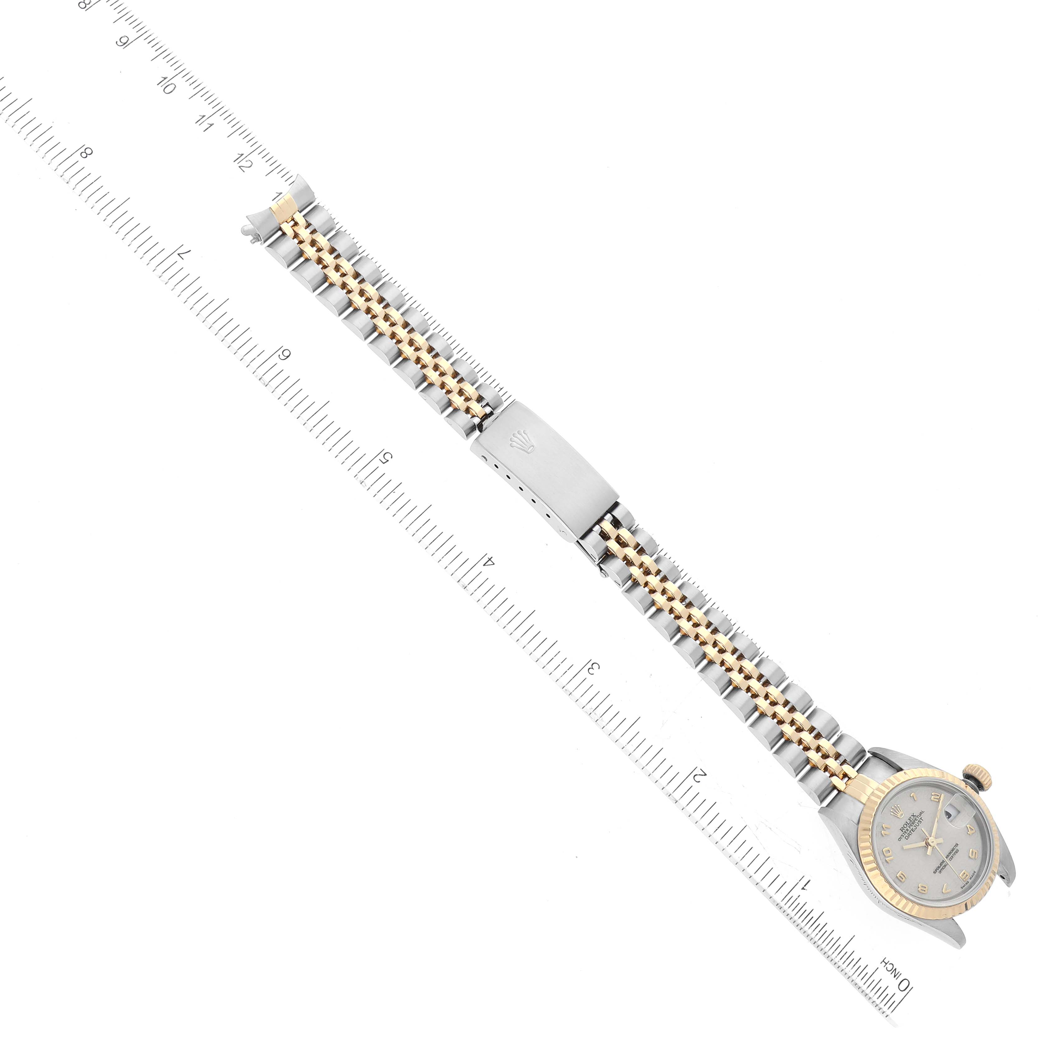 This image shows an overhead view of a Rolex Datejust 79173 Women's Steel and Gold (two tone) White Dial 79173 Women's Steel and Gold (two tone) White Dial watch, displaying its silver and gold bracelet and clasp alongside a ruler.