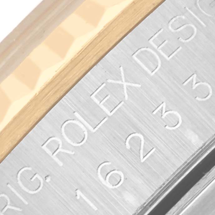 The image shows a close-up of the side of a Rolex Datejust 16233 Men's Steel and Gold (two tone) Grey Dial 16233 Men's Steel and Gold (two tone) Grey Dial, highlighting the engraved text on its metal case.