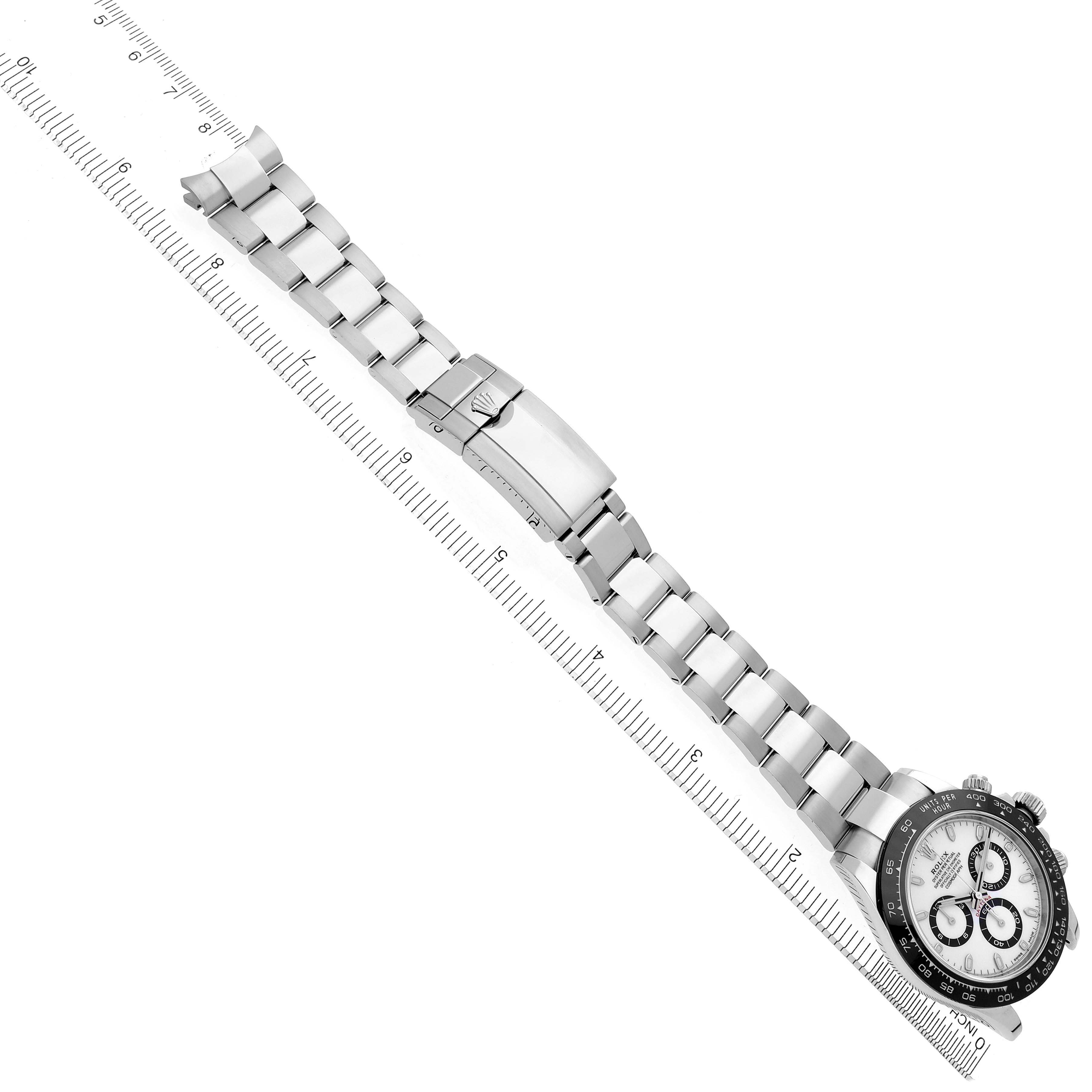 The image shows a Rolex Daytona 116500LN Men's Stainless Steel White Dial 116500LN Men's Stainless Steel White Dial watch laid flat, highlighting its bracelet and clasp alongside a ruler.